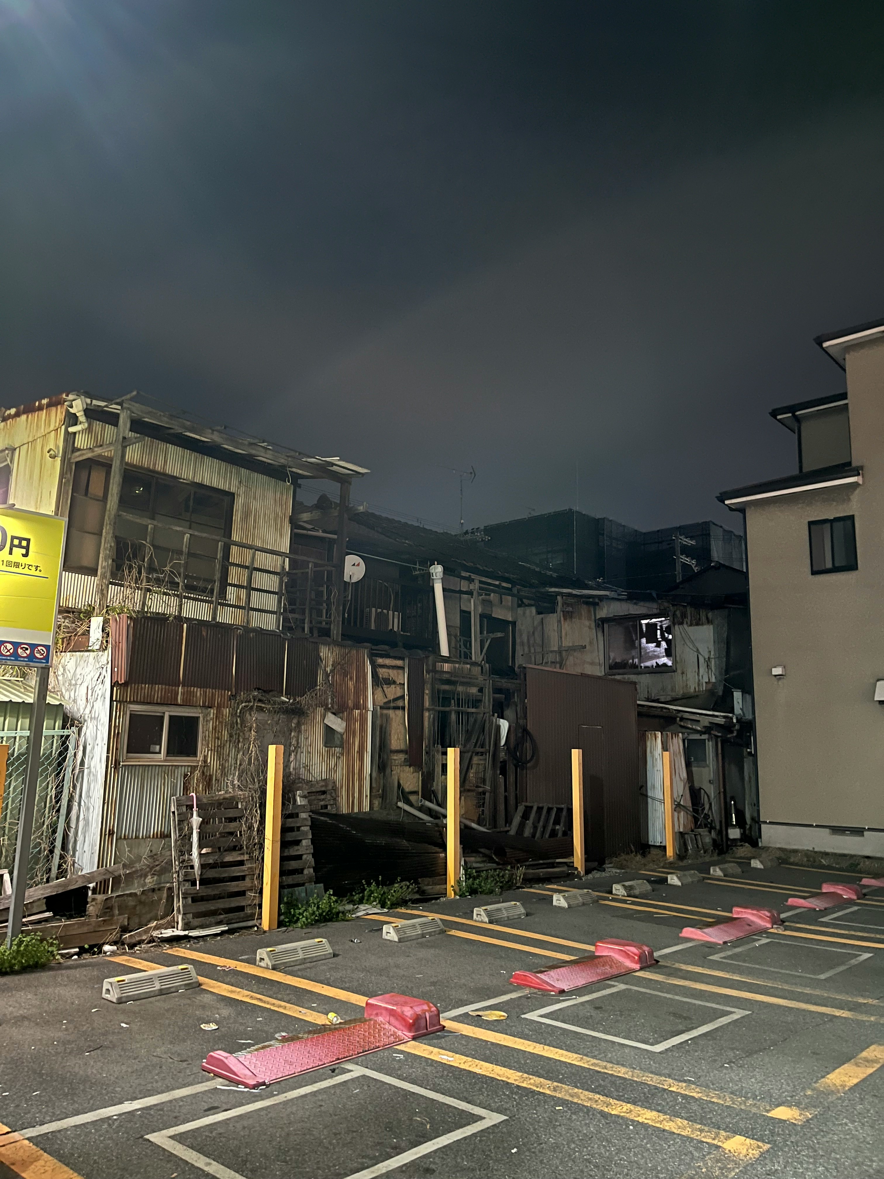路地に並ぶ駐車スペースと古い建物のある住宅街