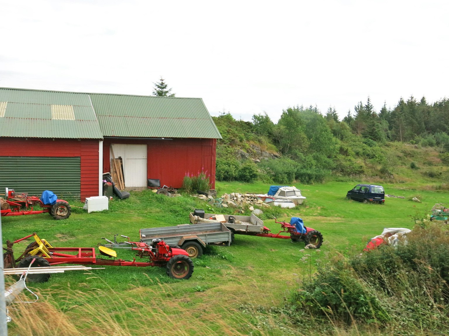 Farm scene featuring a red barn and workers with green grass and surrounding vehicles