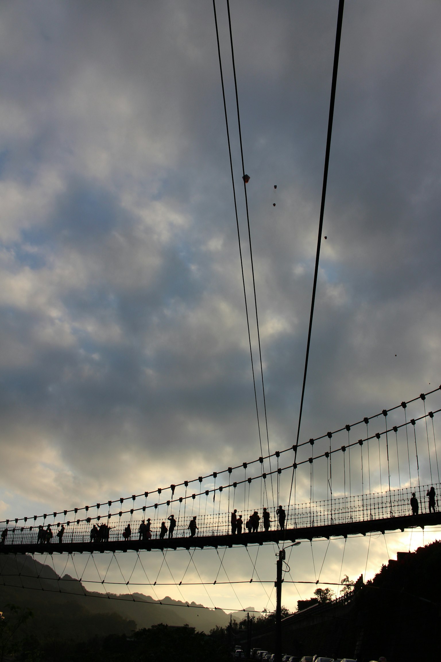 Silueta de un puente con personas caminando contra un cielo nublado