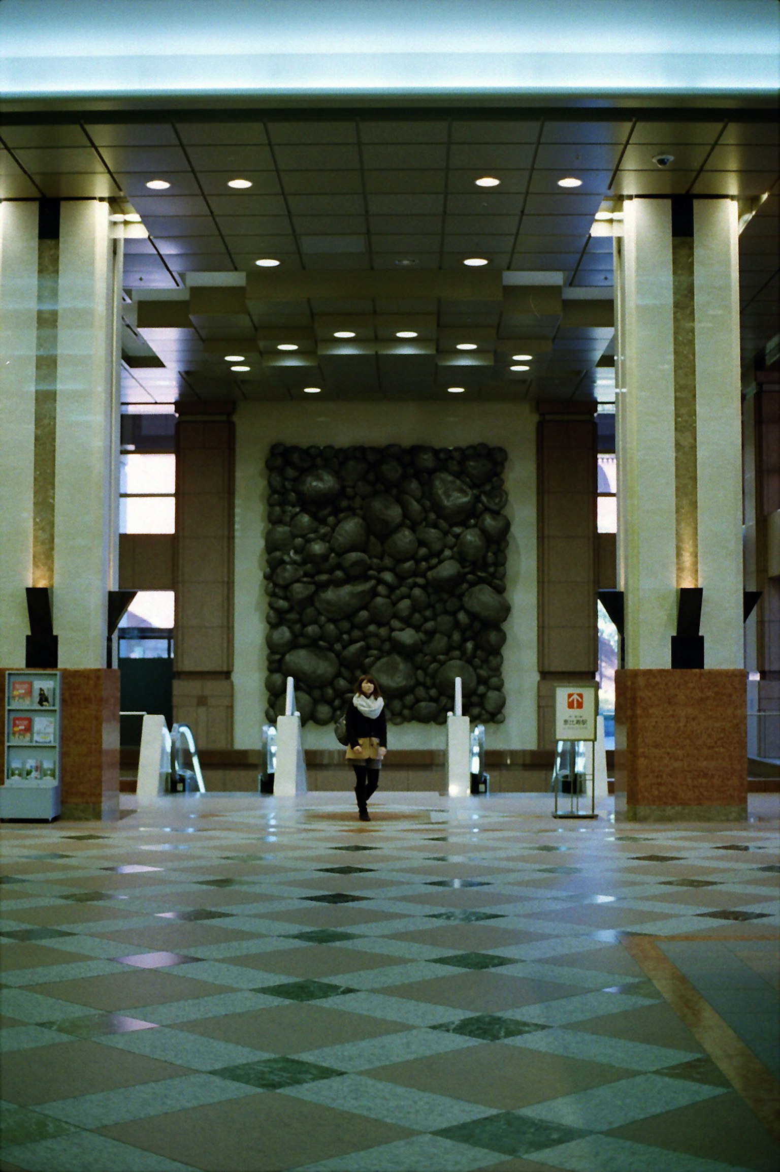 Eine Person steht in einer geräumigen Lobby mit einem skulpturalen Hintergrund