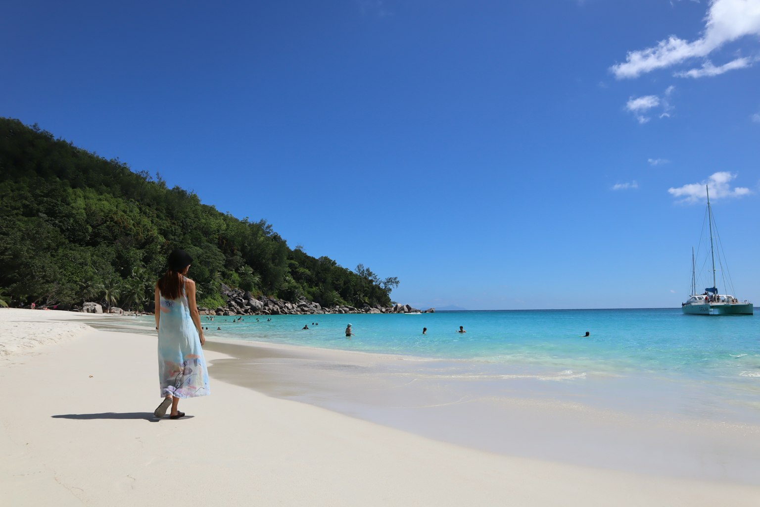 Une femme marchant le long d'une plage de sable blanc avec une eau claire