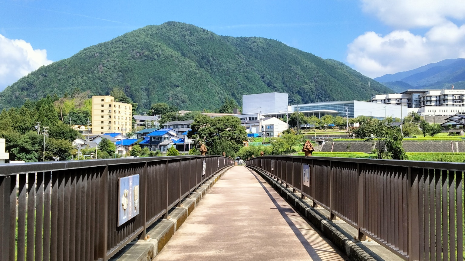 View of a green mountain and buildings from a bridge