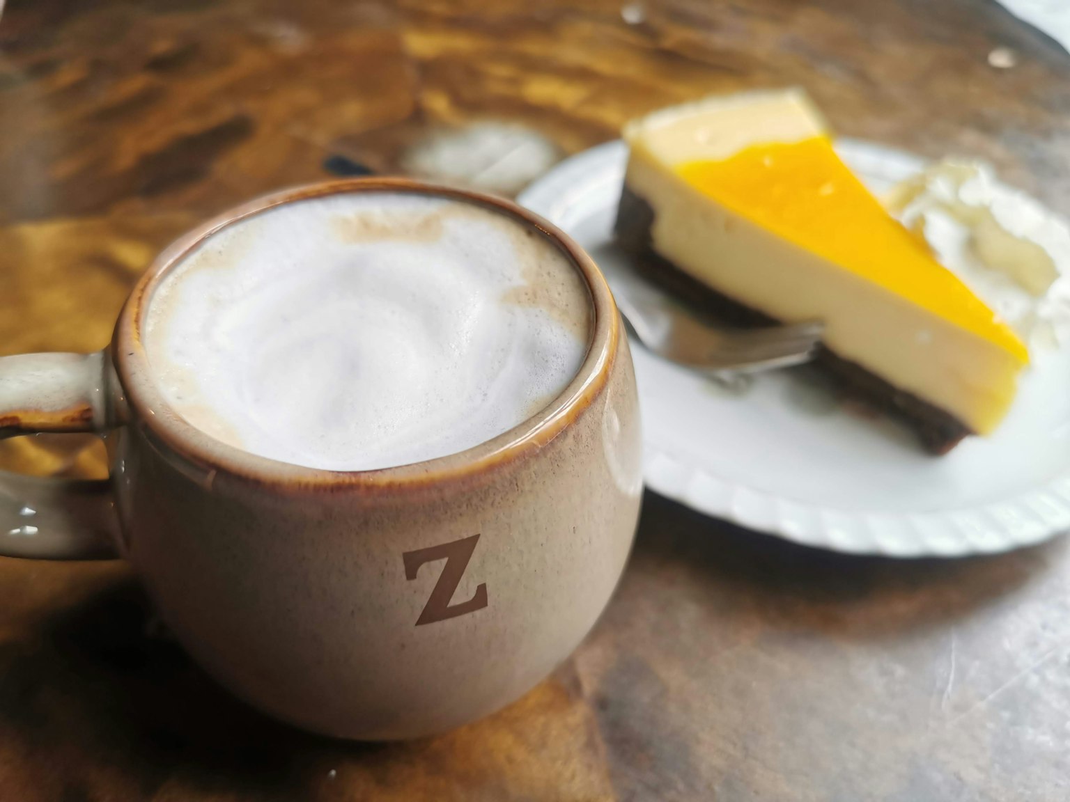 ถ้วยกาแฟฟองข้างเค้กชีสส้ม