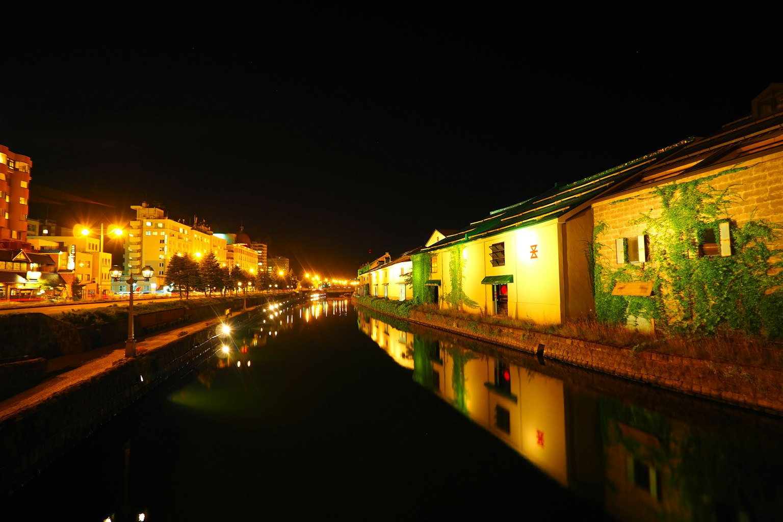 Vista nocturna de edificios a lo largo del canal con luces reflejadas