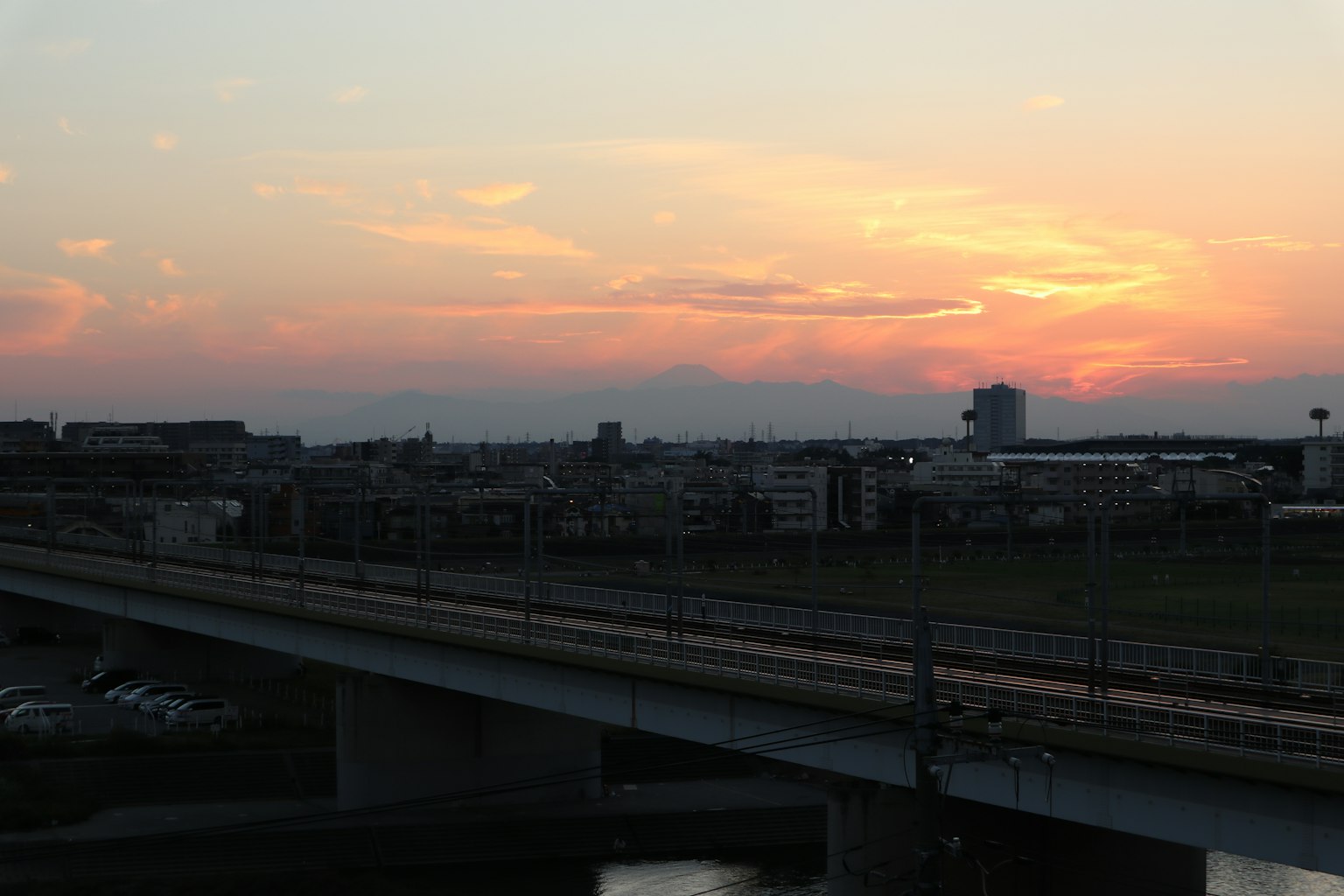 Paesaggio urbano con un ponte ferroviario contro un tramonto
