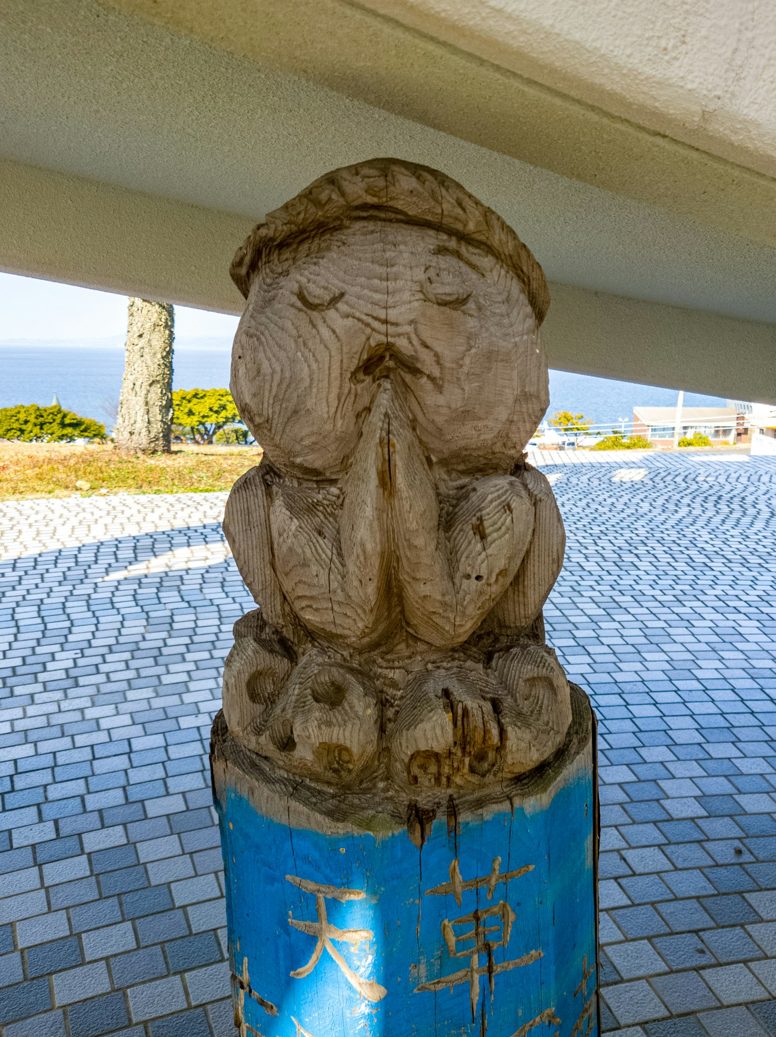 木制祈祷角色雕像，蓝色底座上显示汉字