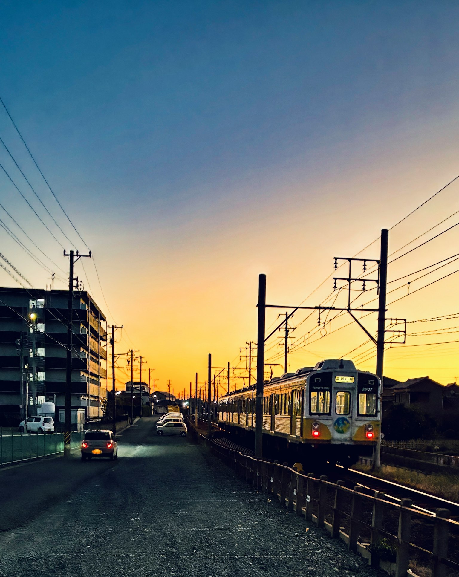 夕焼けの空の下で走る電車と近くの建物