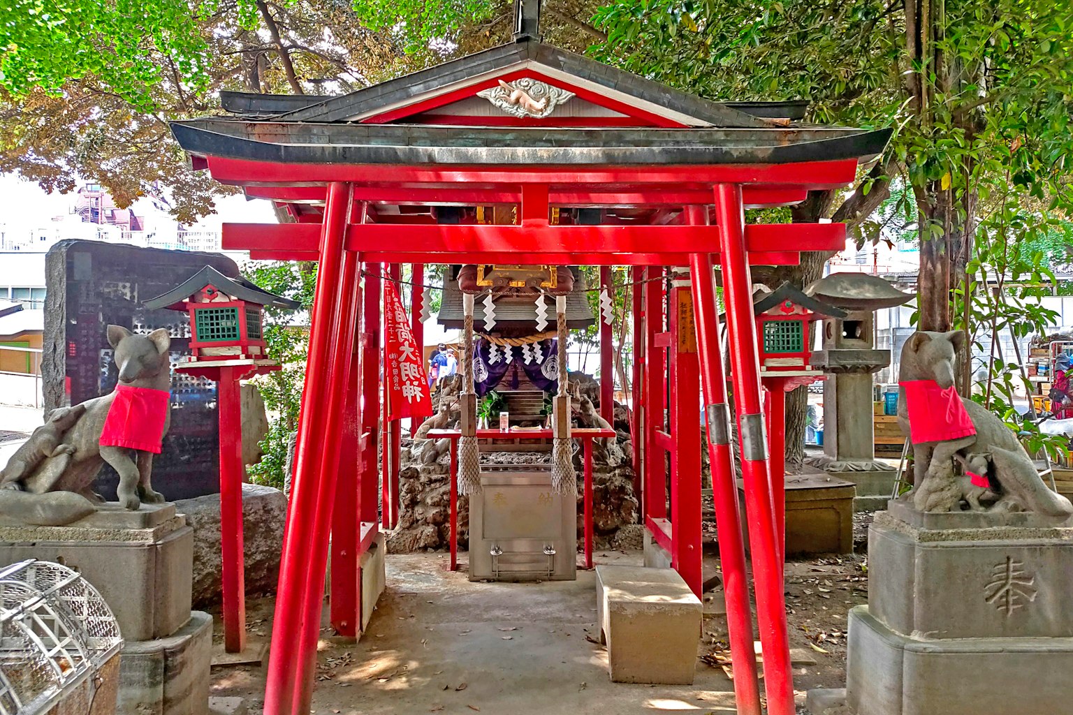 Entrata di un santuario con torii rossi e statue di pietra circostanti