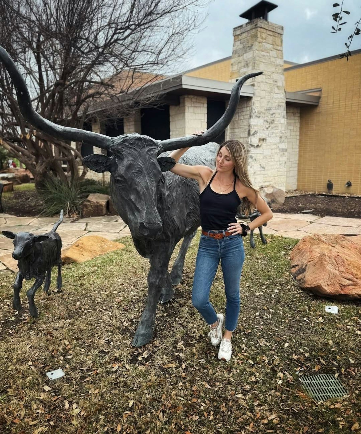 女性が牛の彫刻のそばに立っている風景