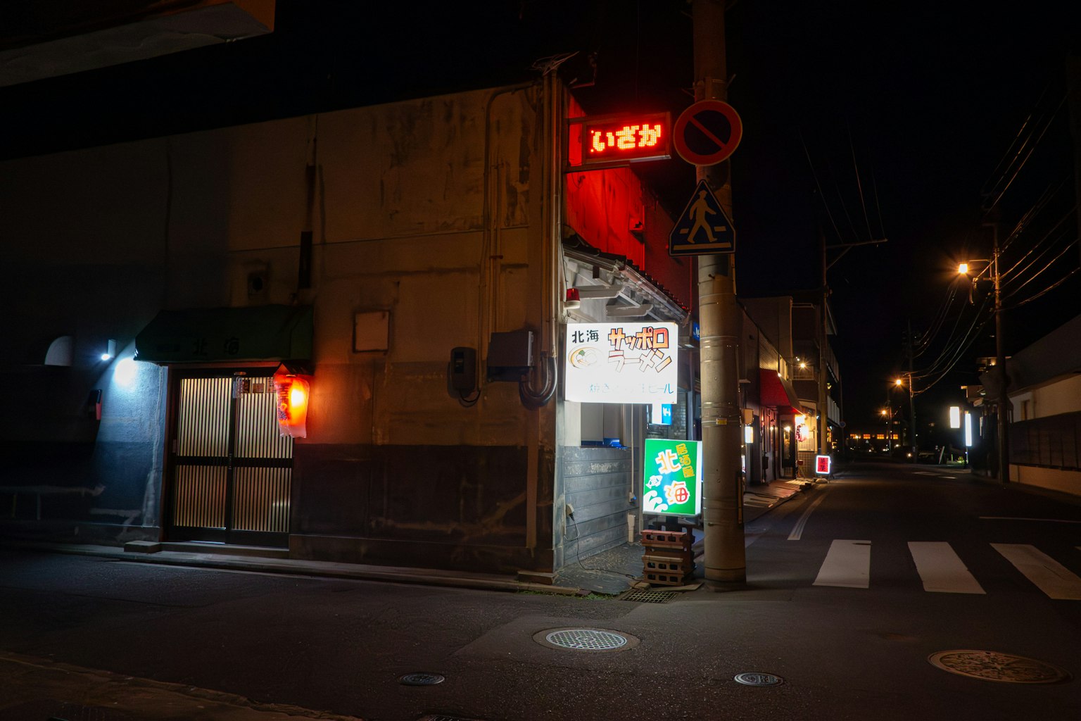 Extérieur d'un restaurant la nuit avec un panneau rouge et un éclairage lumineux