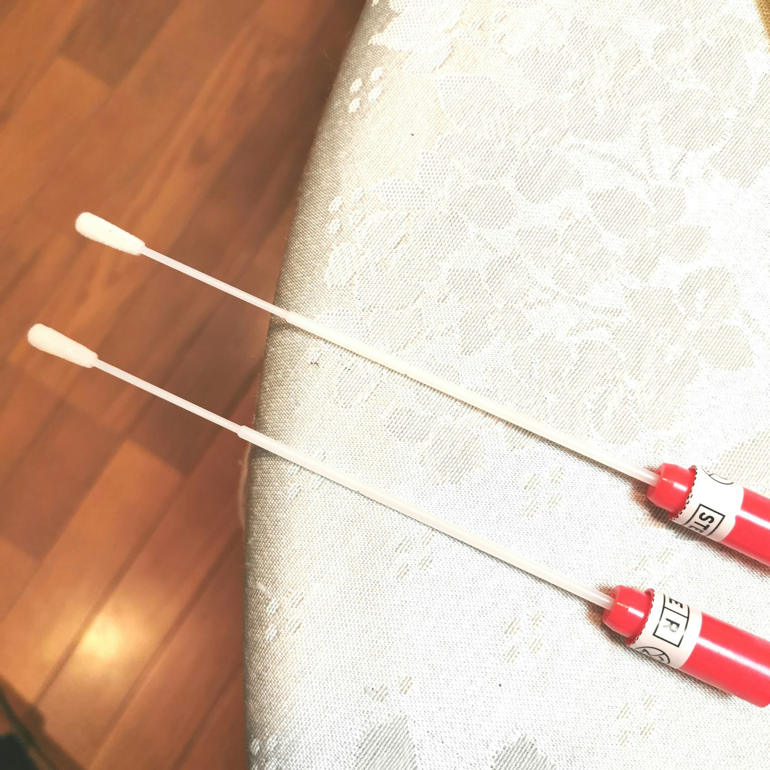 Zwei Wattestäbchen mit roten Griffen nebeneinander platziert