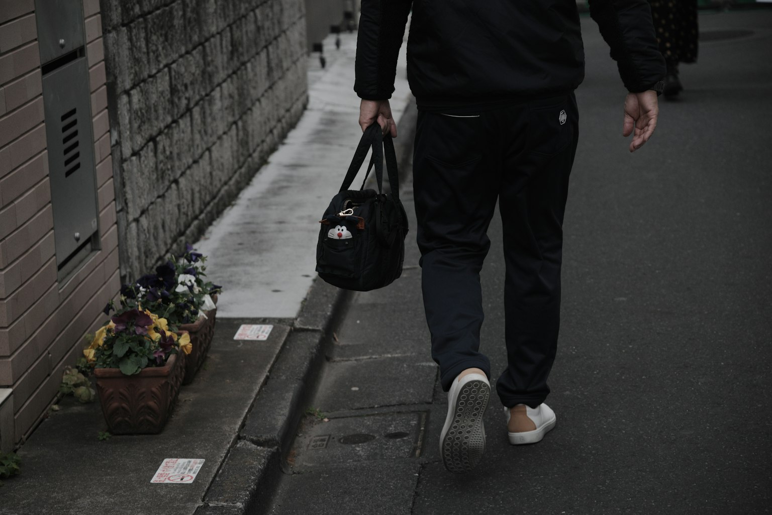 在黑暗街道上走的男人拿着黑色包