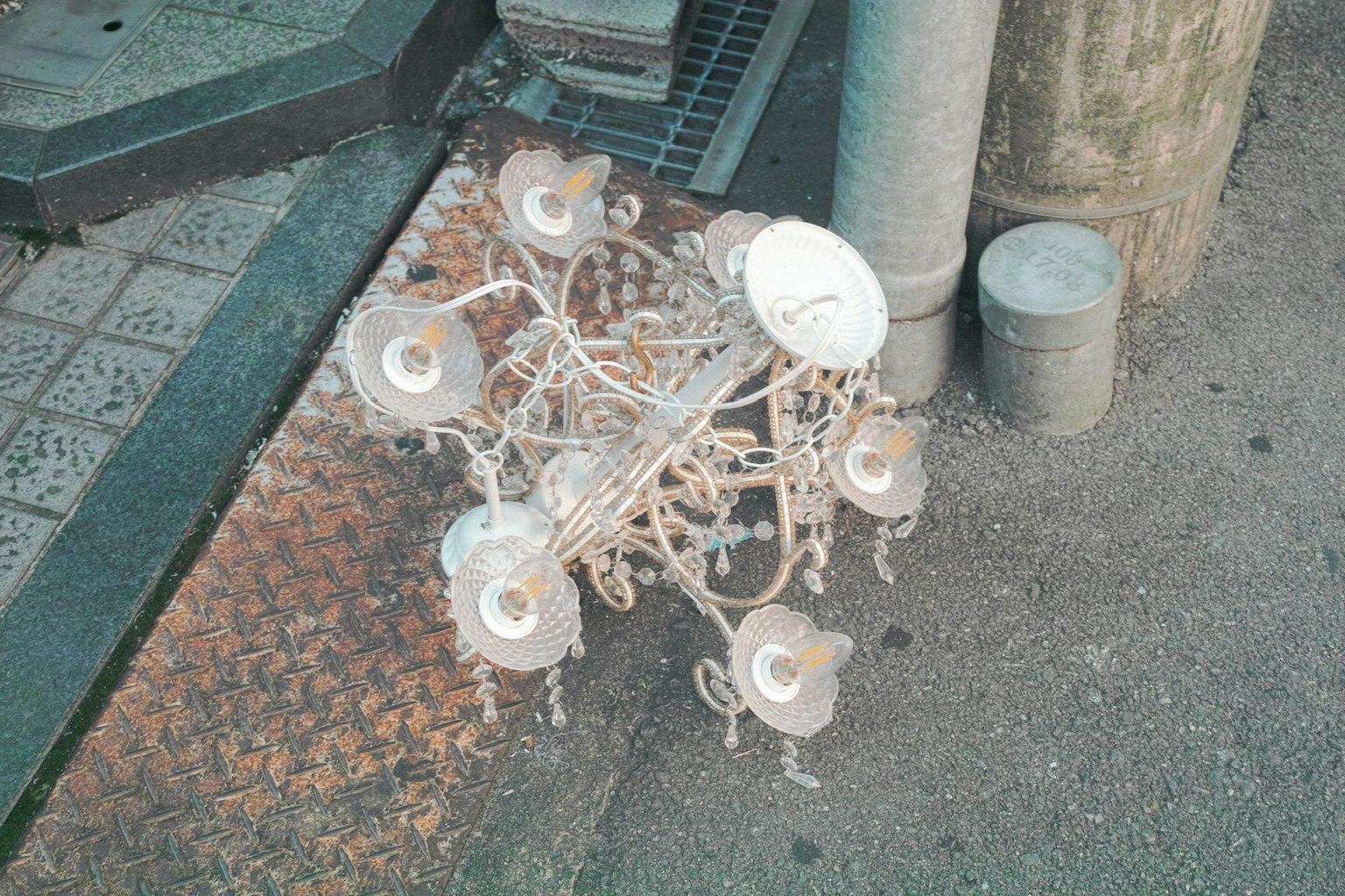 街の歩道に置かれた白いシャンデリアの破損した部分