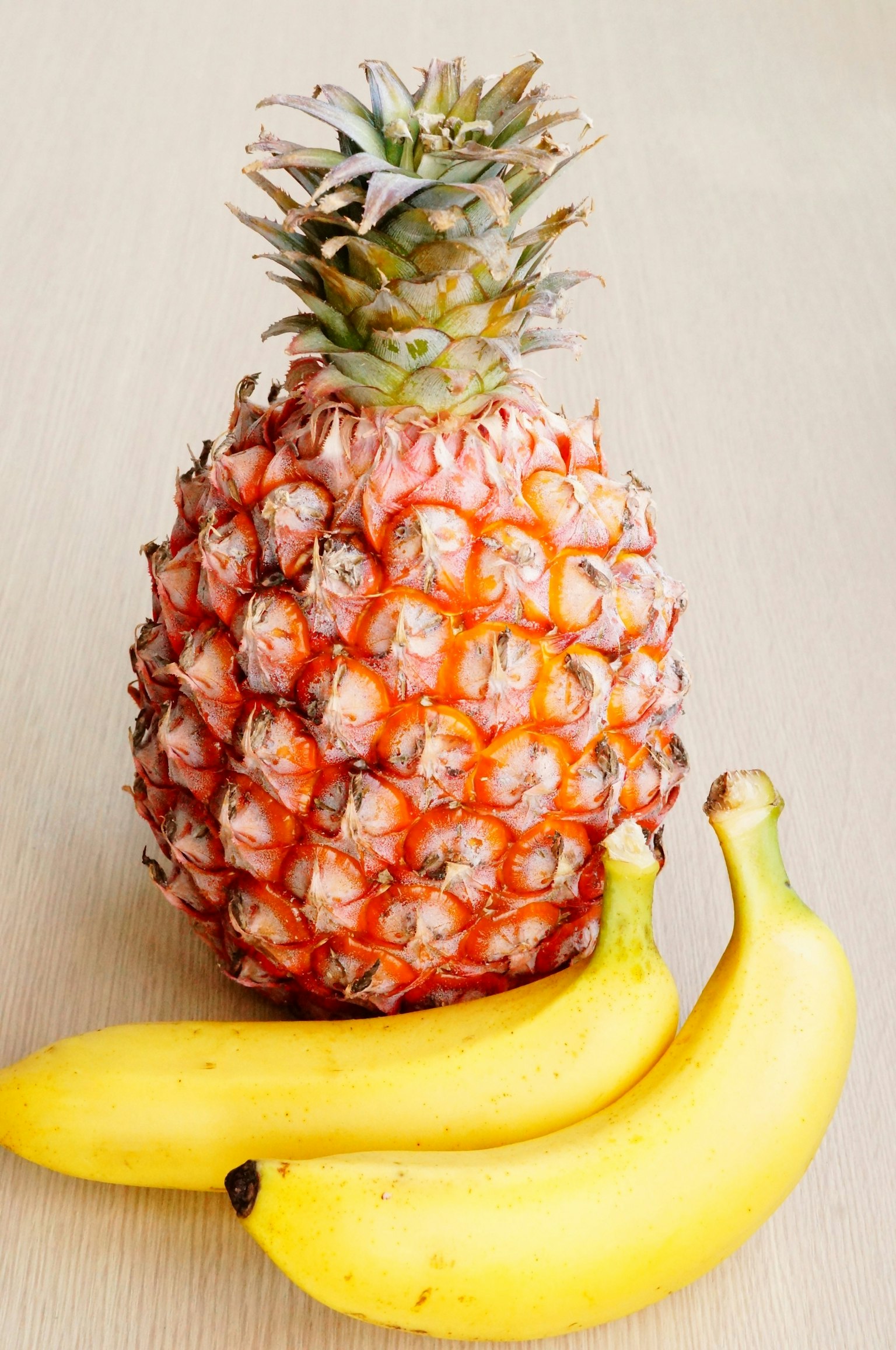 Foto de una piña y plátanos sobre una superficie de madera