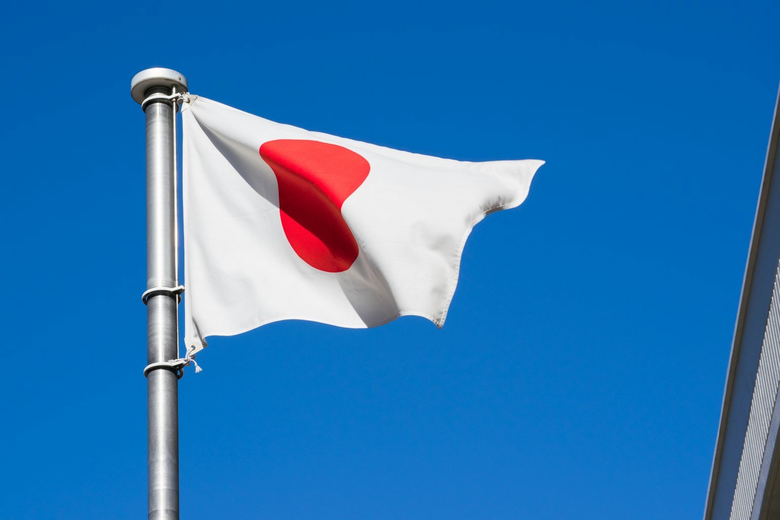 Japanese national flag with a red circle on a white field waving against a blue sky