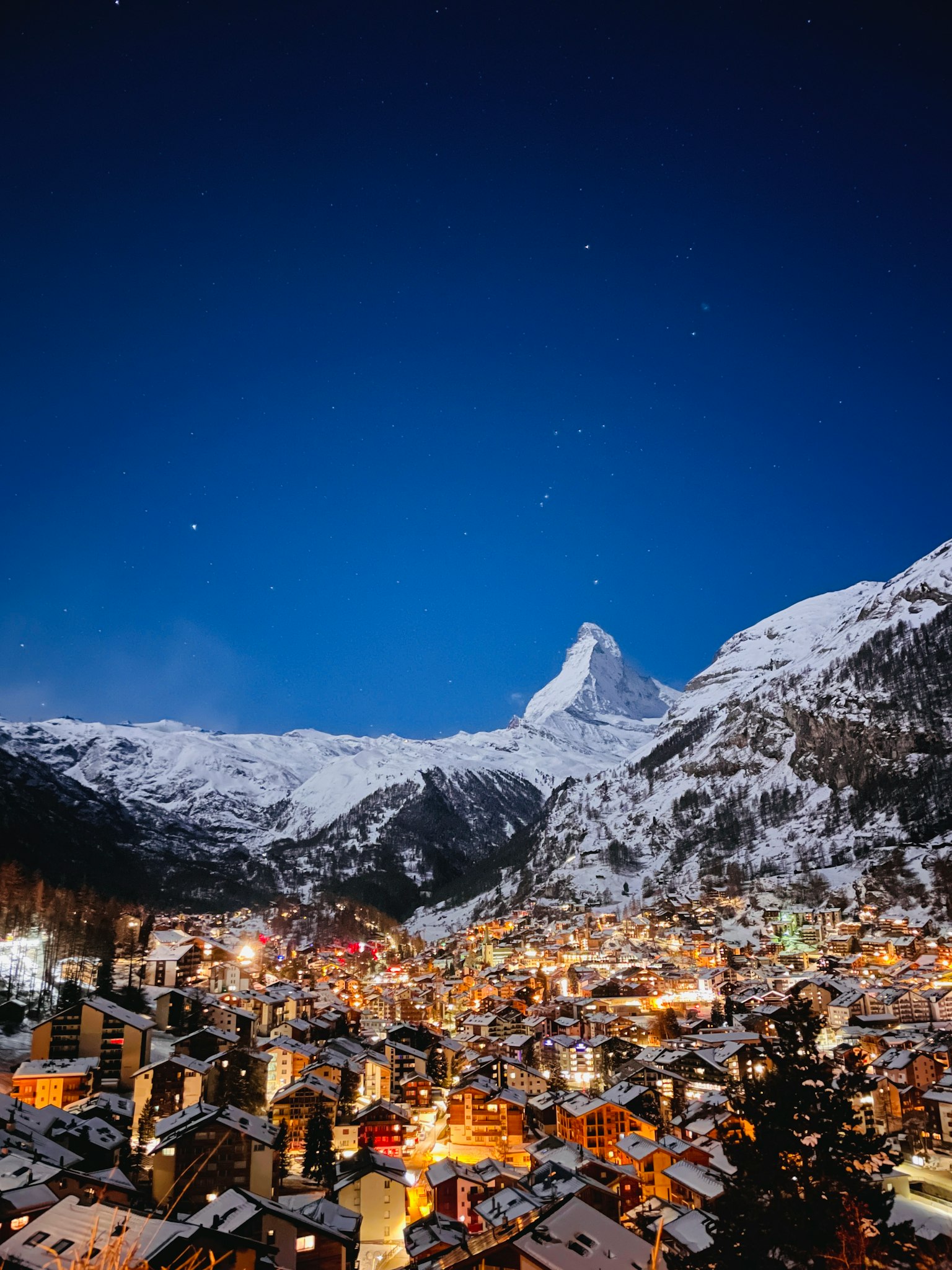 雪に覆われた山々と美しい夜空の下に広がる小さな町の景色
