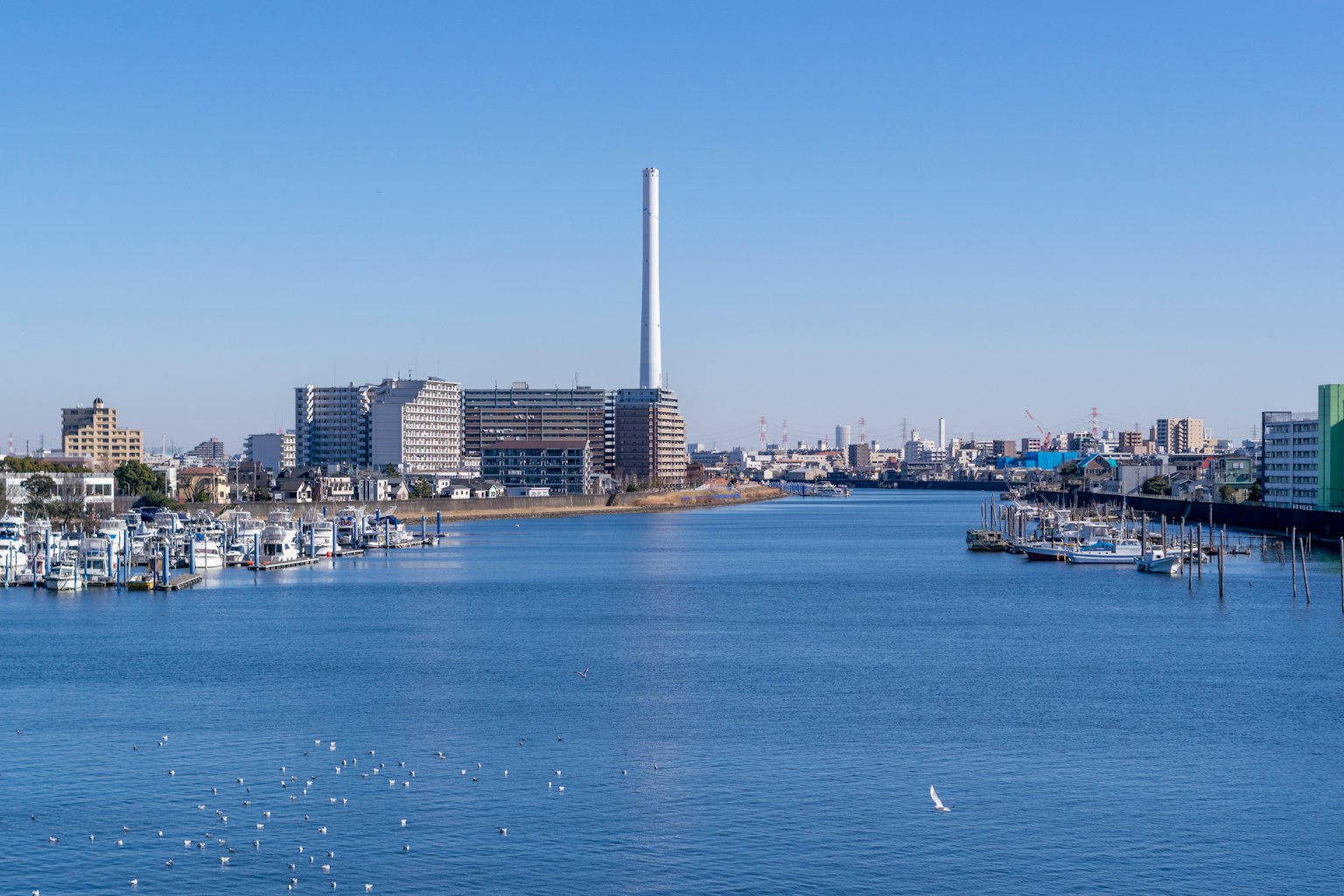 晴朗藍天下河流與船隻及工業建築的風景