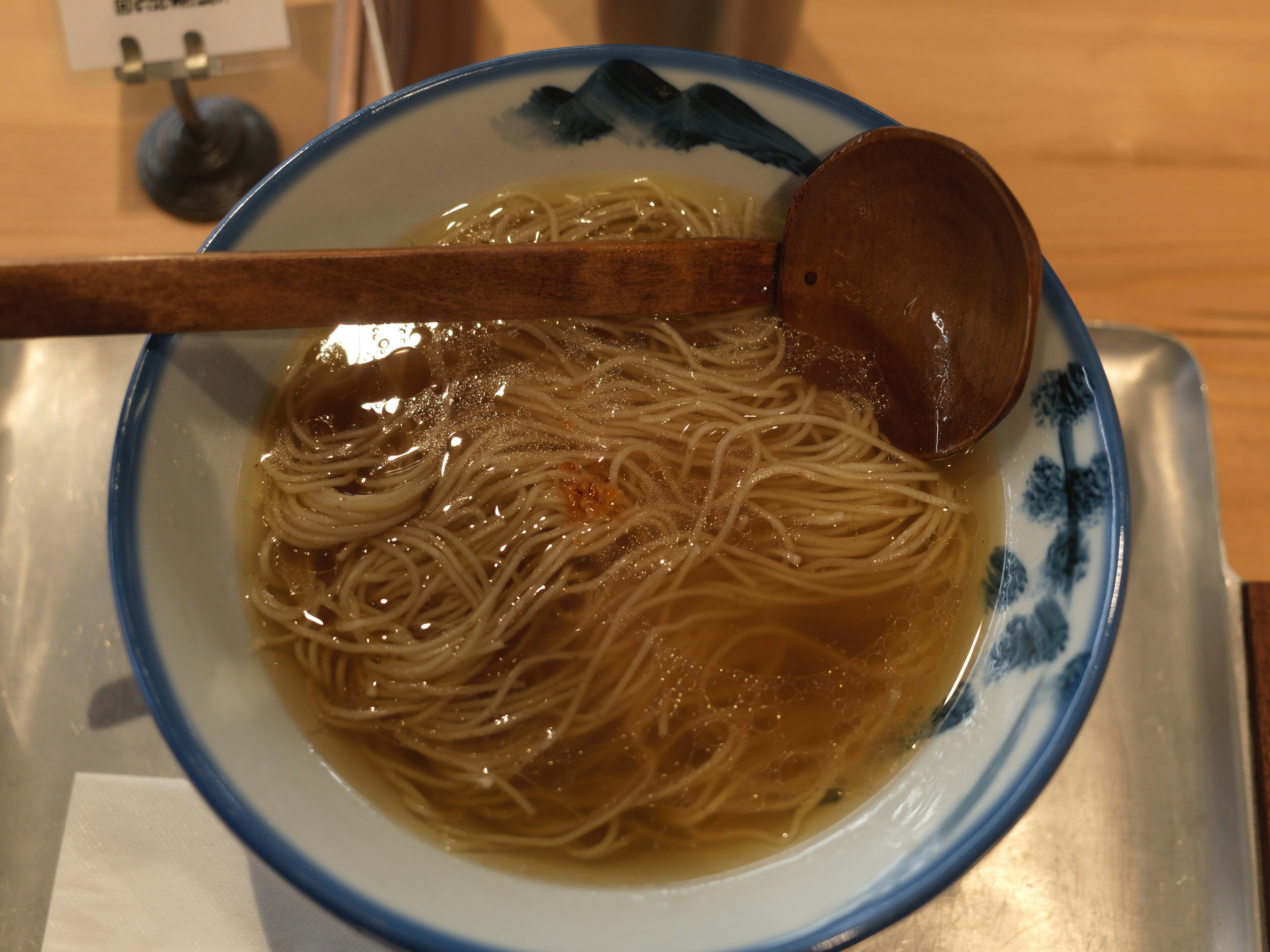 木製スプーンののった器に盛られた細麺のスープ