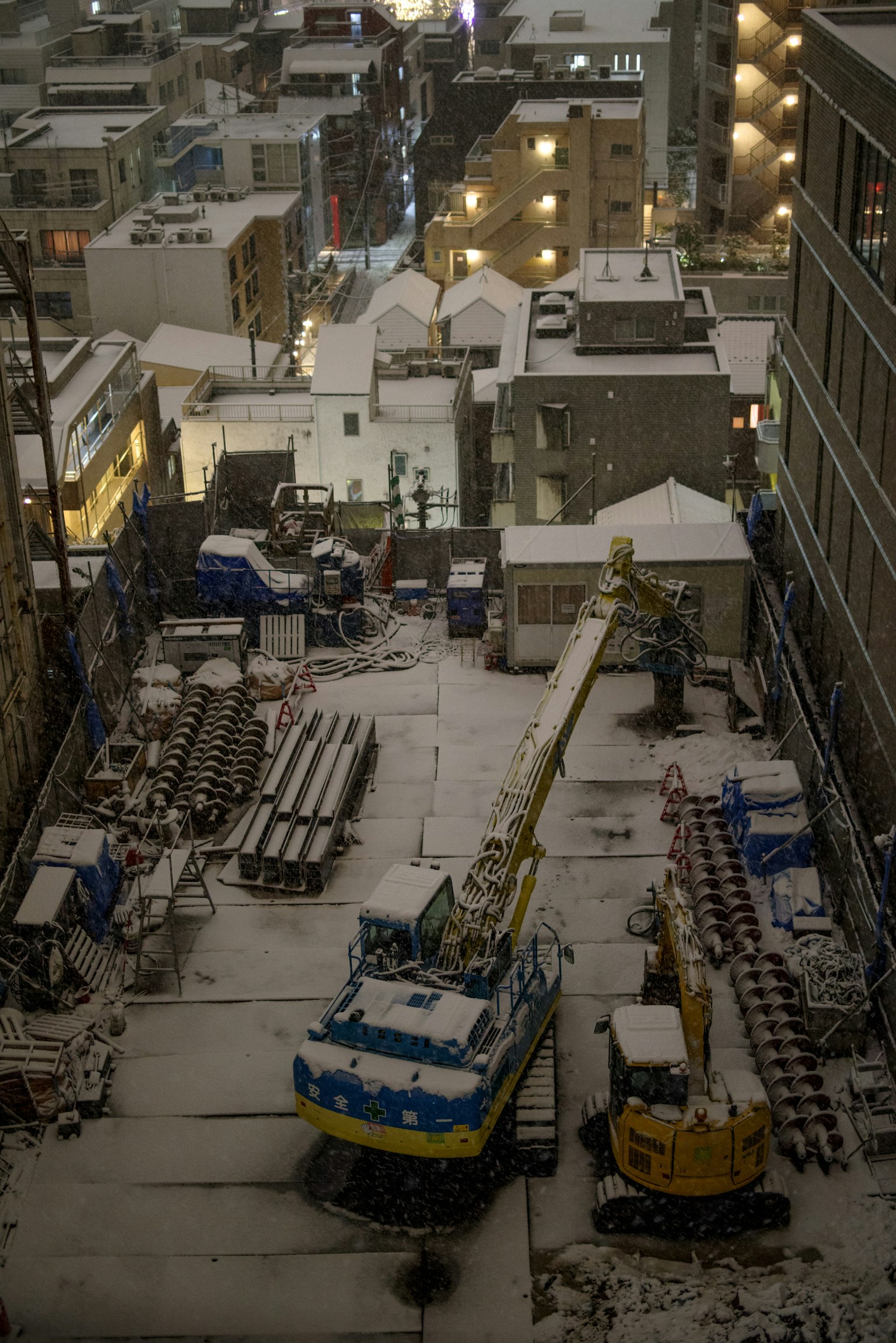 Baustelle in einer verschneiten städtischen Umgebung mit Maschinen und Materialien