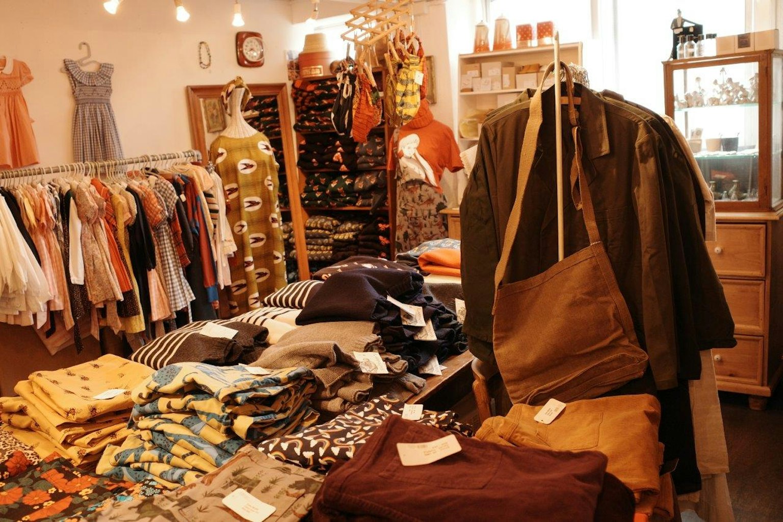 小型精品店的内部，五颜六色的衣服展示在架子上，桌子上摆放着各种服装