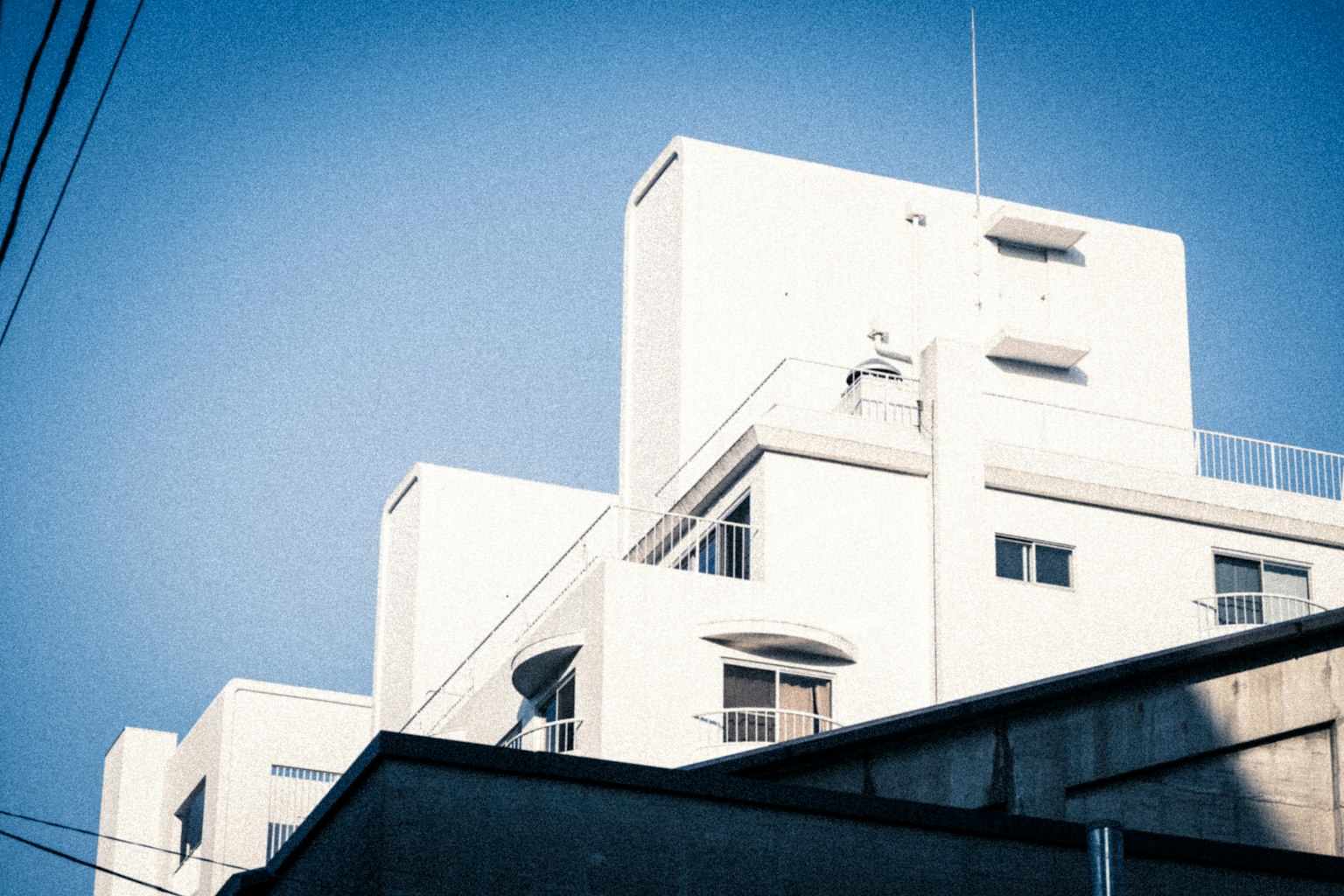 Weißes Gebäude vor blauem Himmel, das moderne Architektur zeigt
