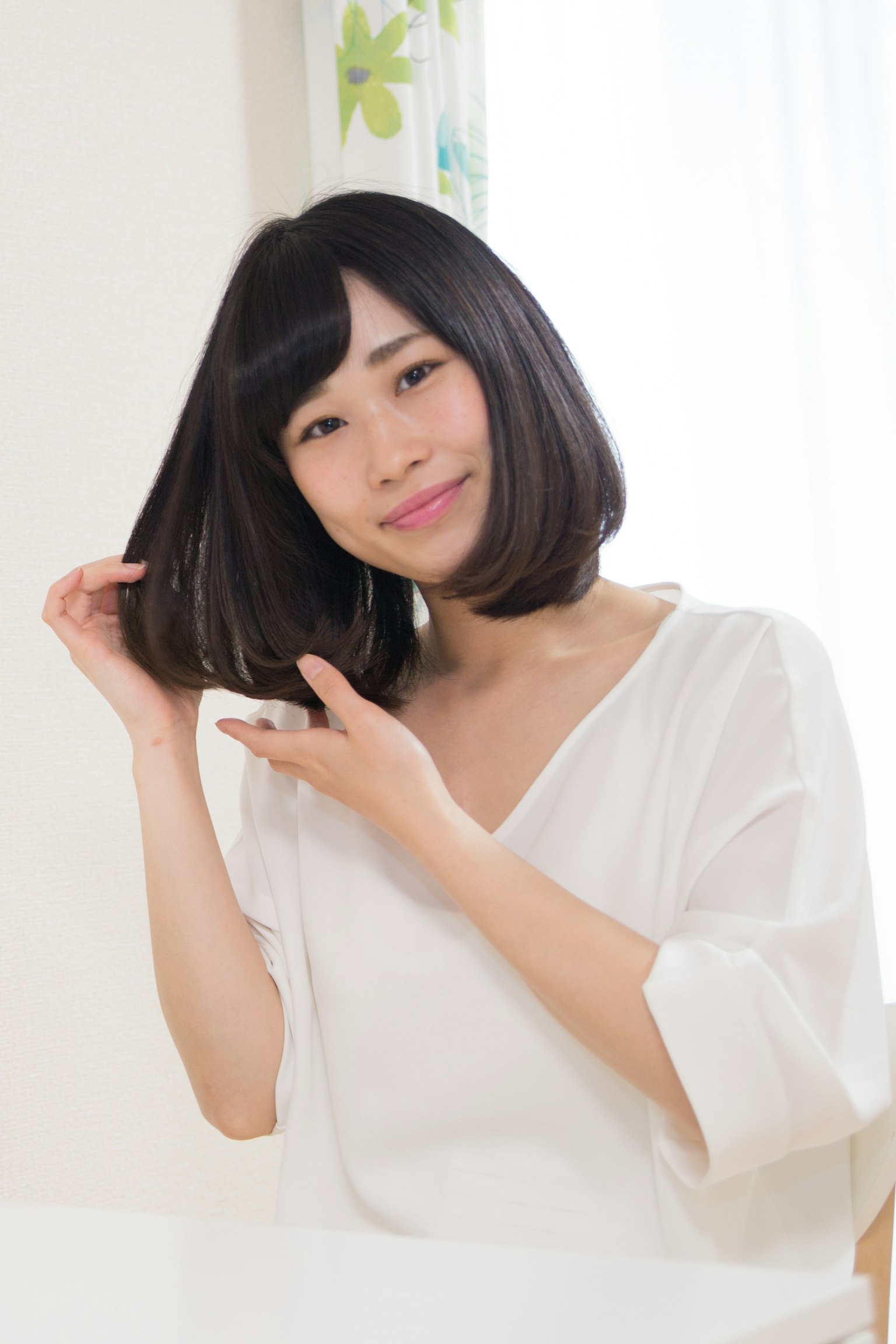 Woman in white clothing adjusting her hair
