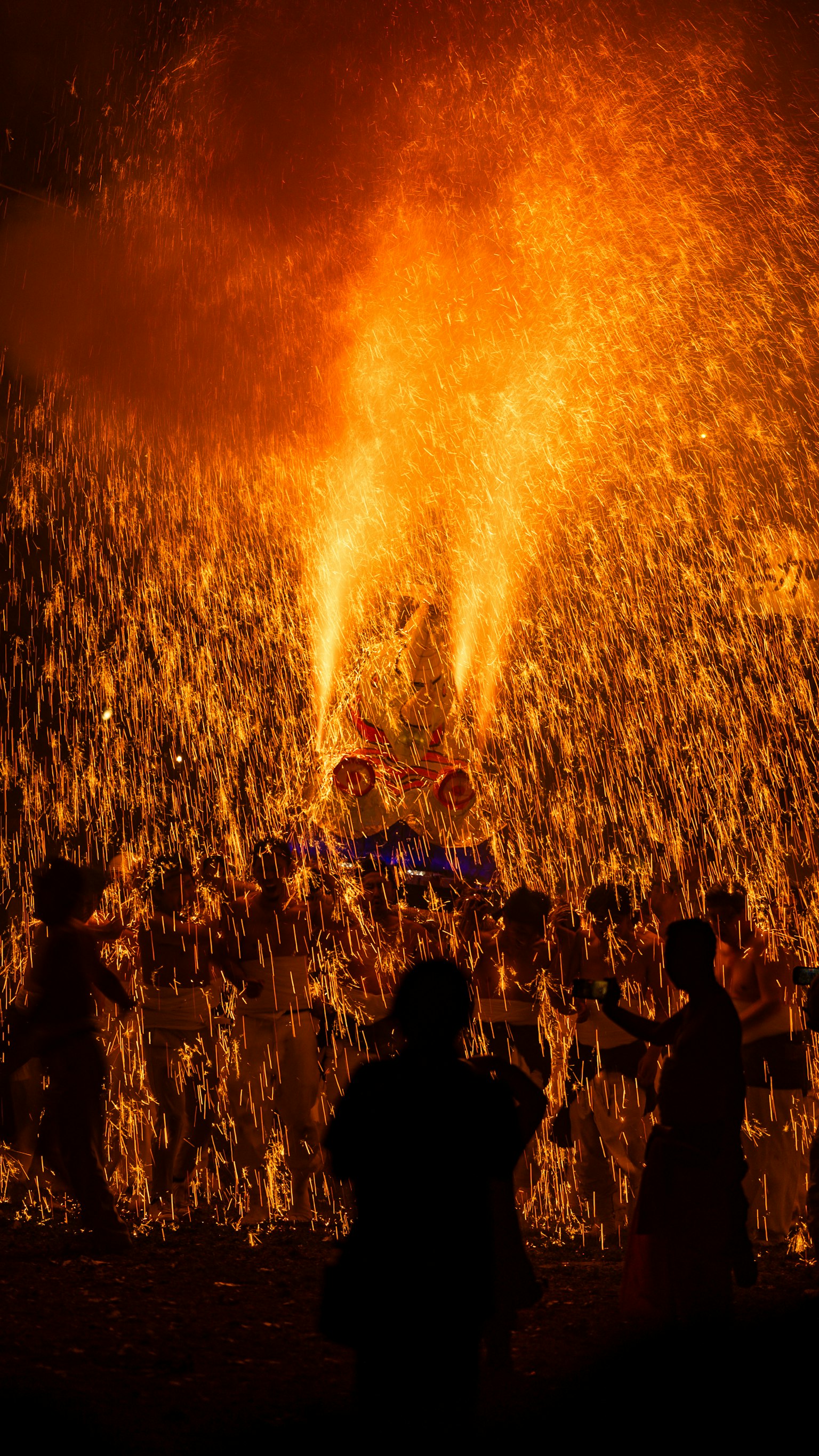Scena di festival con persone che ballano tra le fiamme e silhouette
