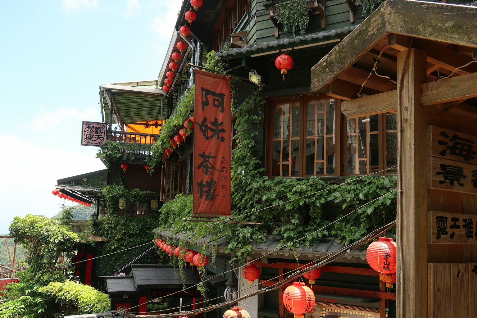Traditionelles taiwanesisches Gebäude mit Grünbewuchs und roten Laternen