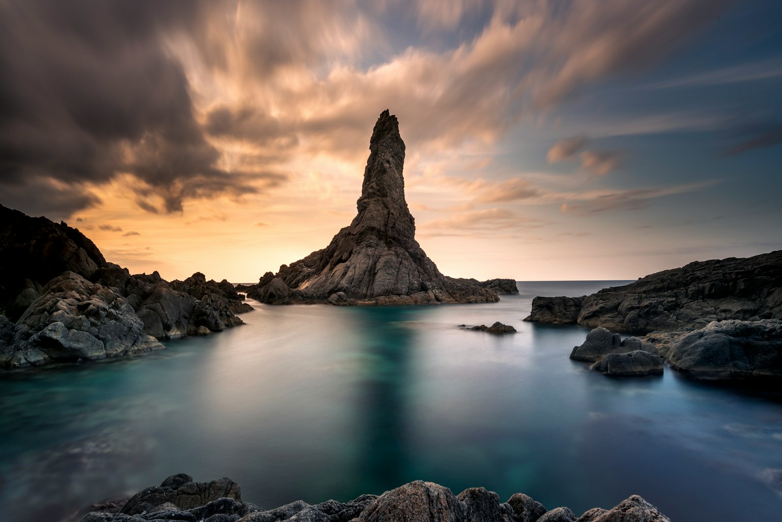 Stunning coastal landscape featuring a towering rock formation illuminated by sunset light
