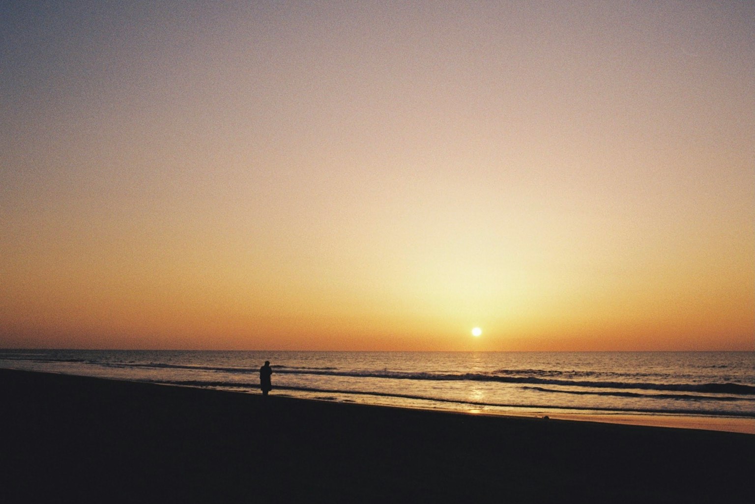 一个人在宁静的海滩上凝视日落