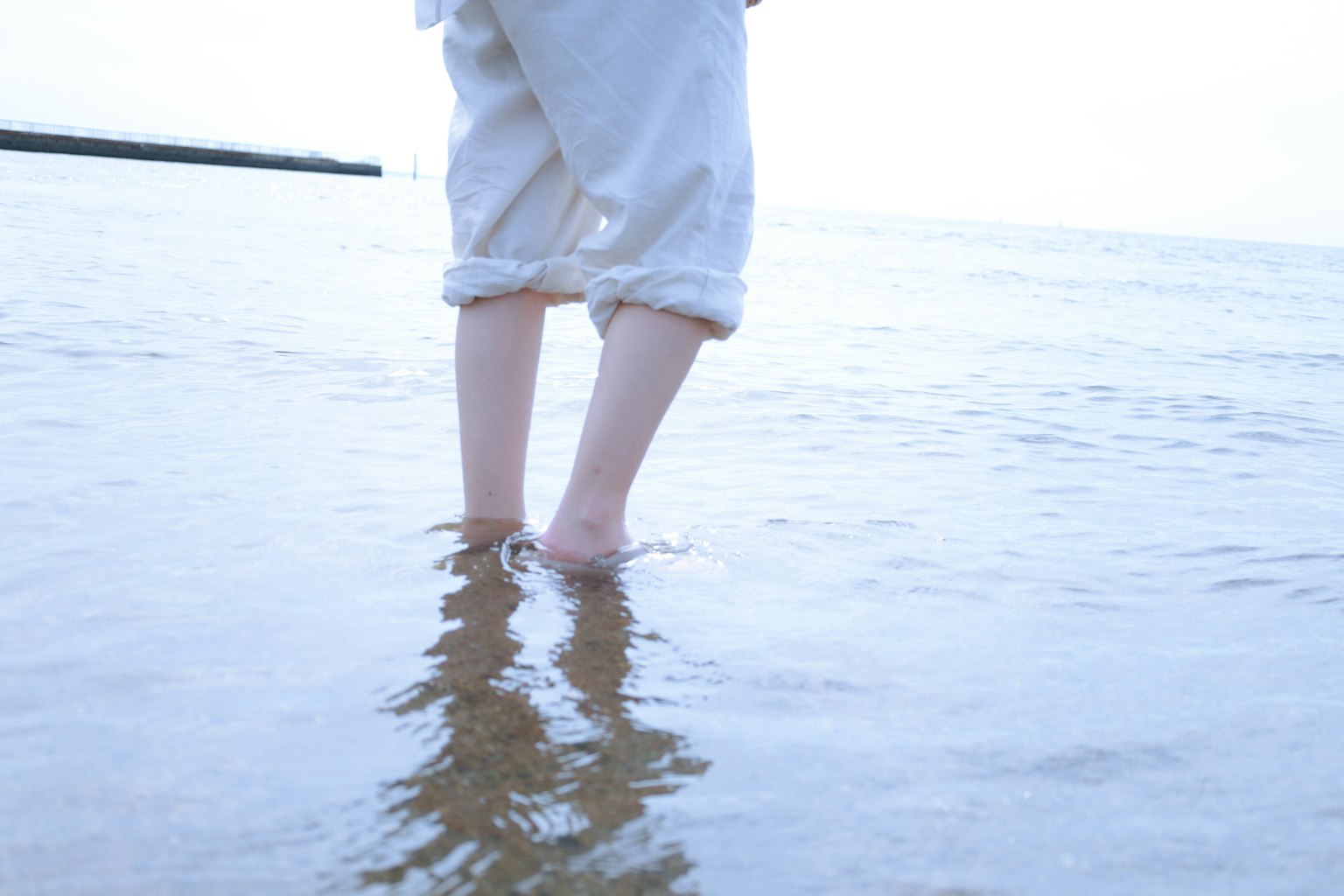 穿著白色衣服的人站在海灘的淺水中