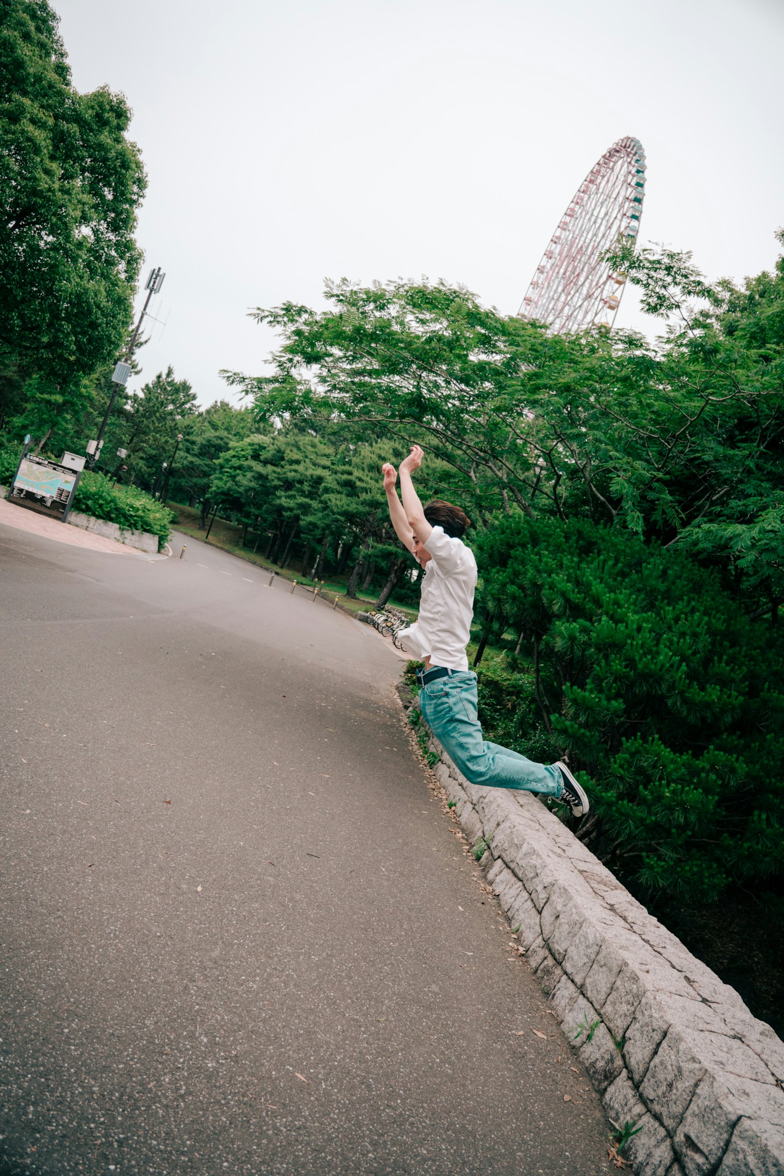 Man jumping in a park surrounded by green trees
