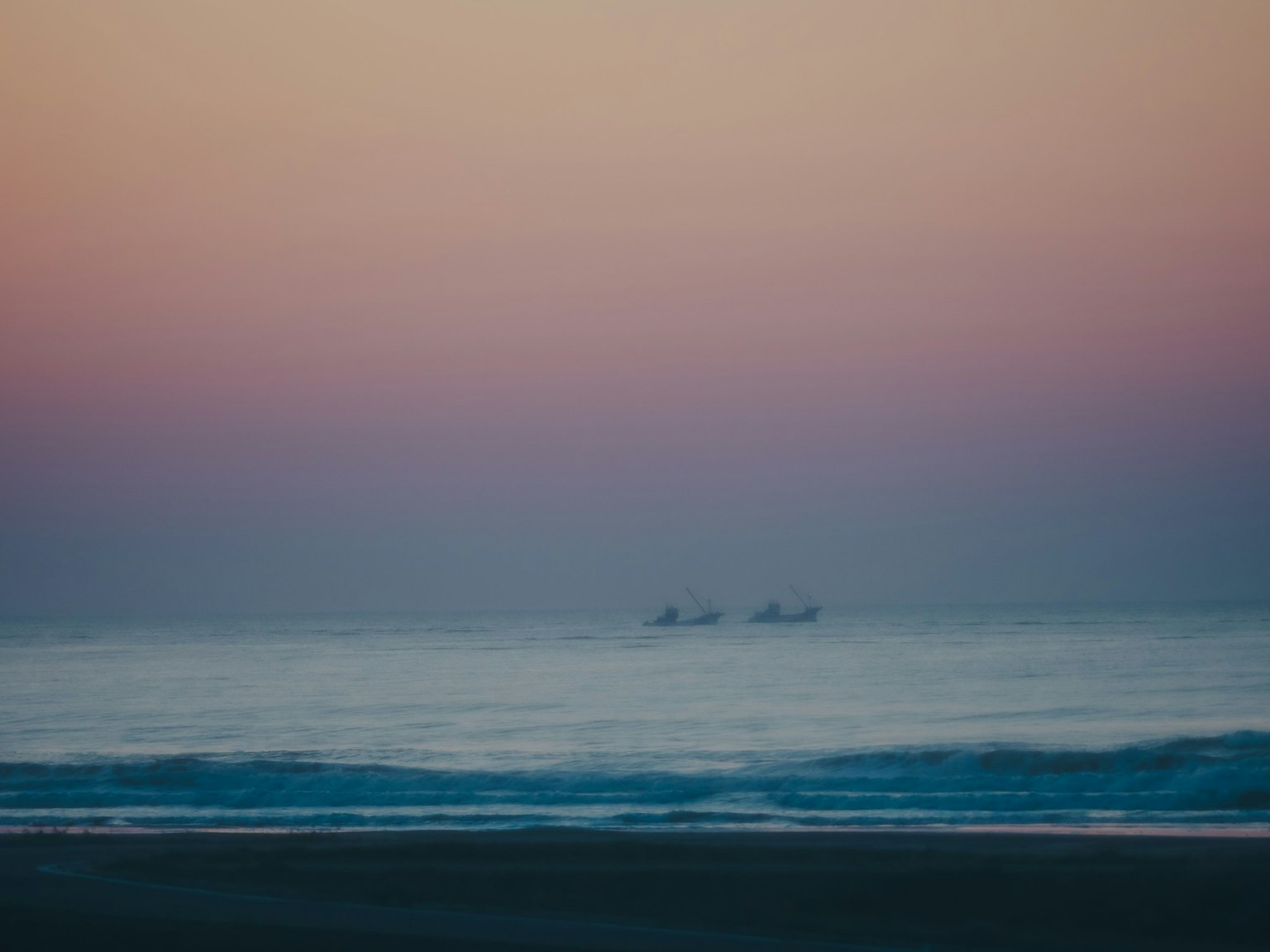 Boats floating on the sea with a soft sunset sky