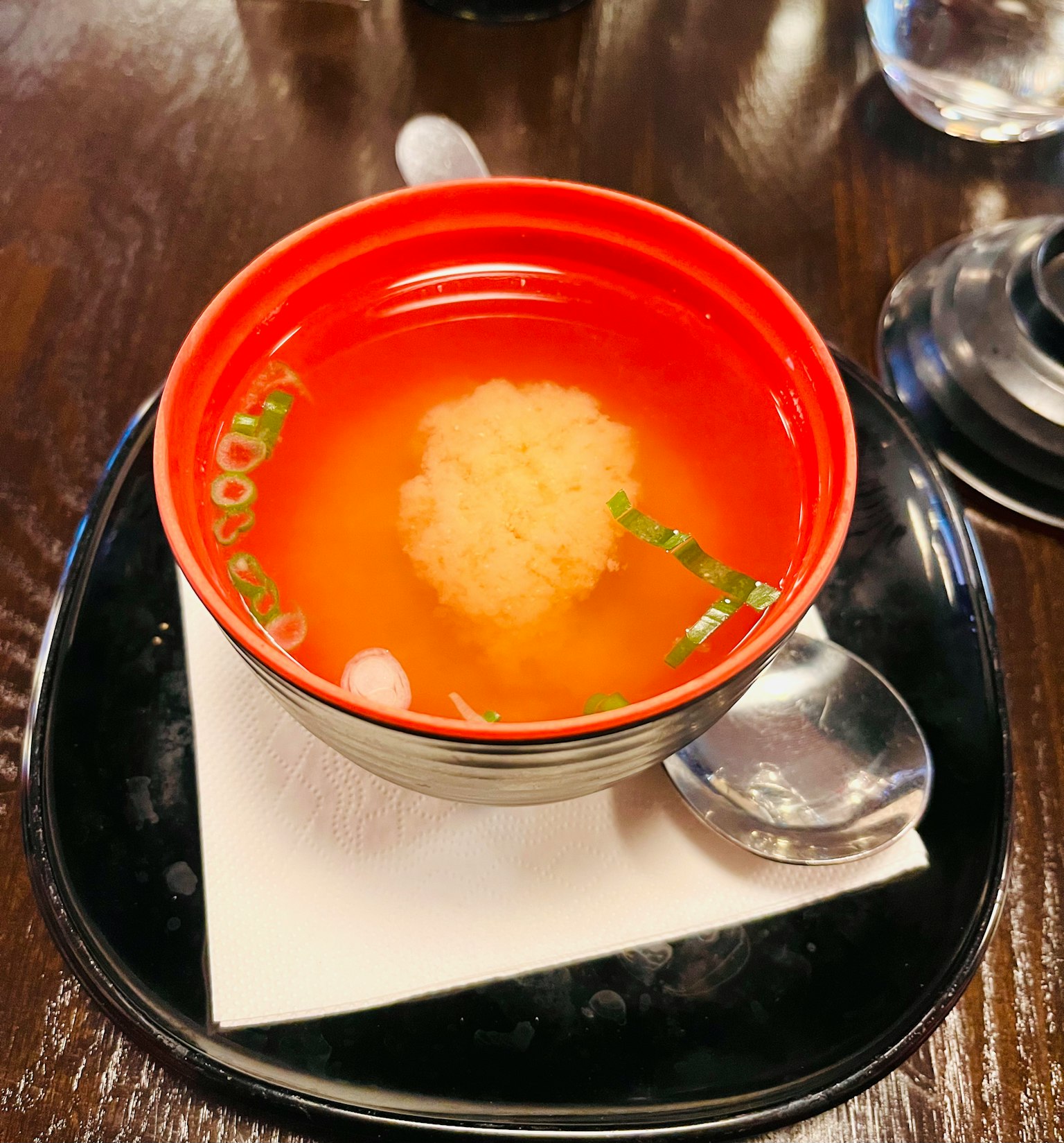 紅色碗中盛放的味噌湯，配有蔥花