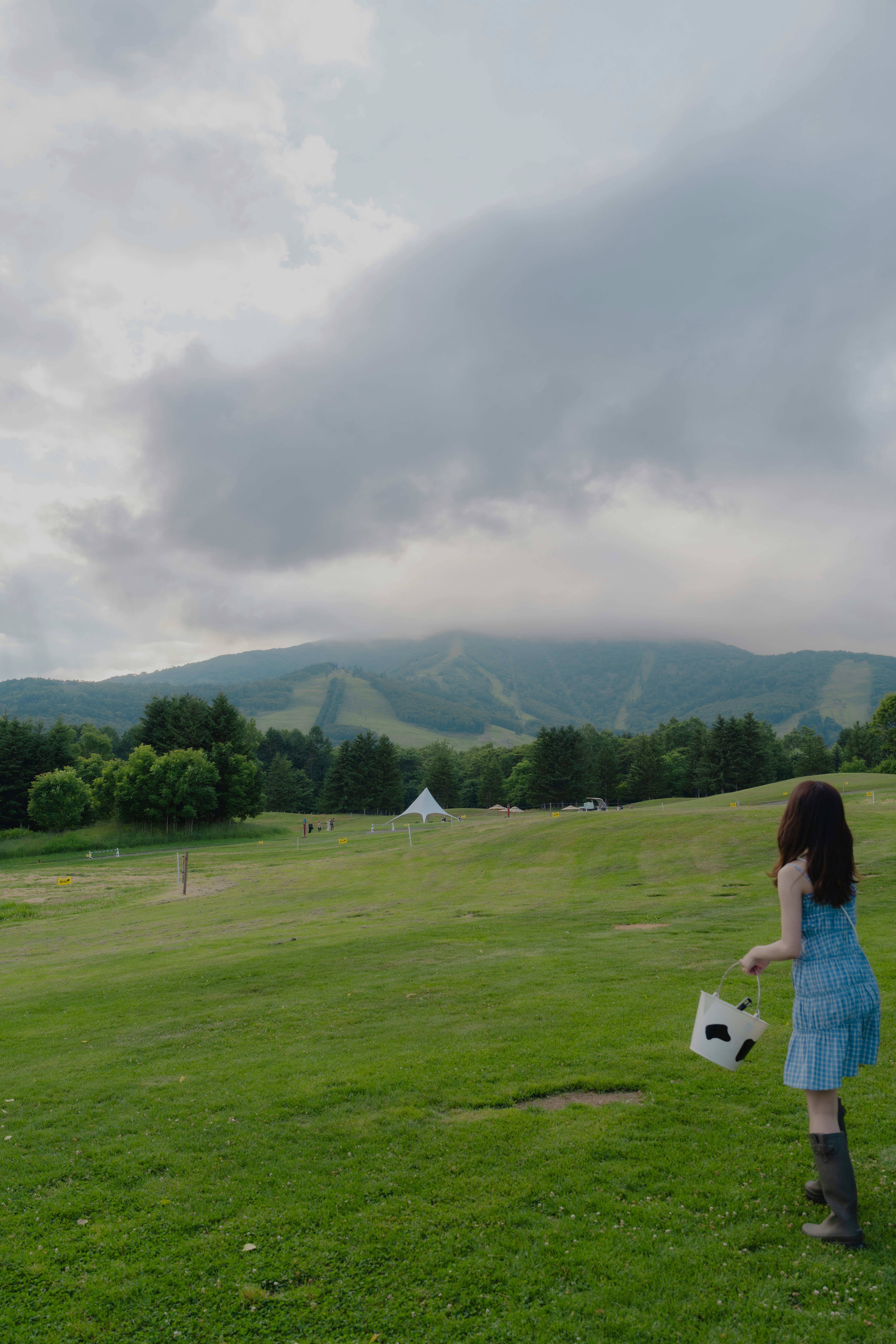 草原の小道を歩く女性と遠くの山並み
