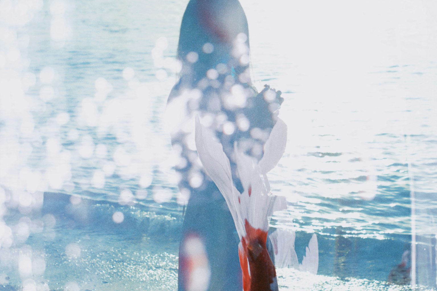 Silhouette of a woman standing by the water with reflections of light on the surface