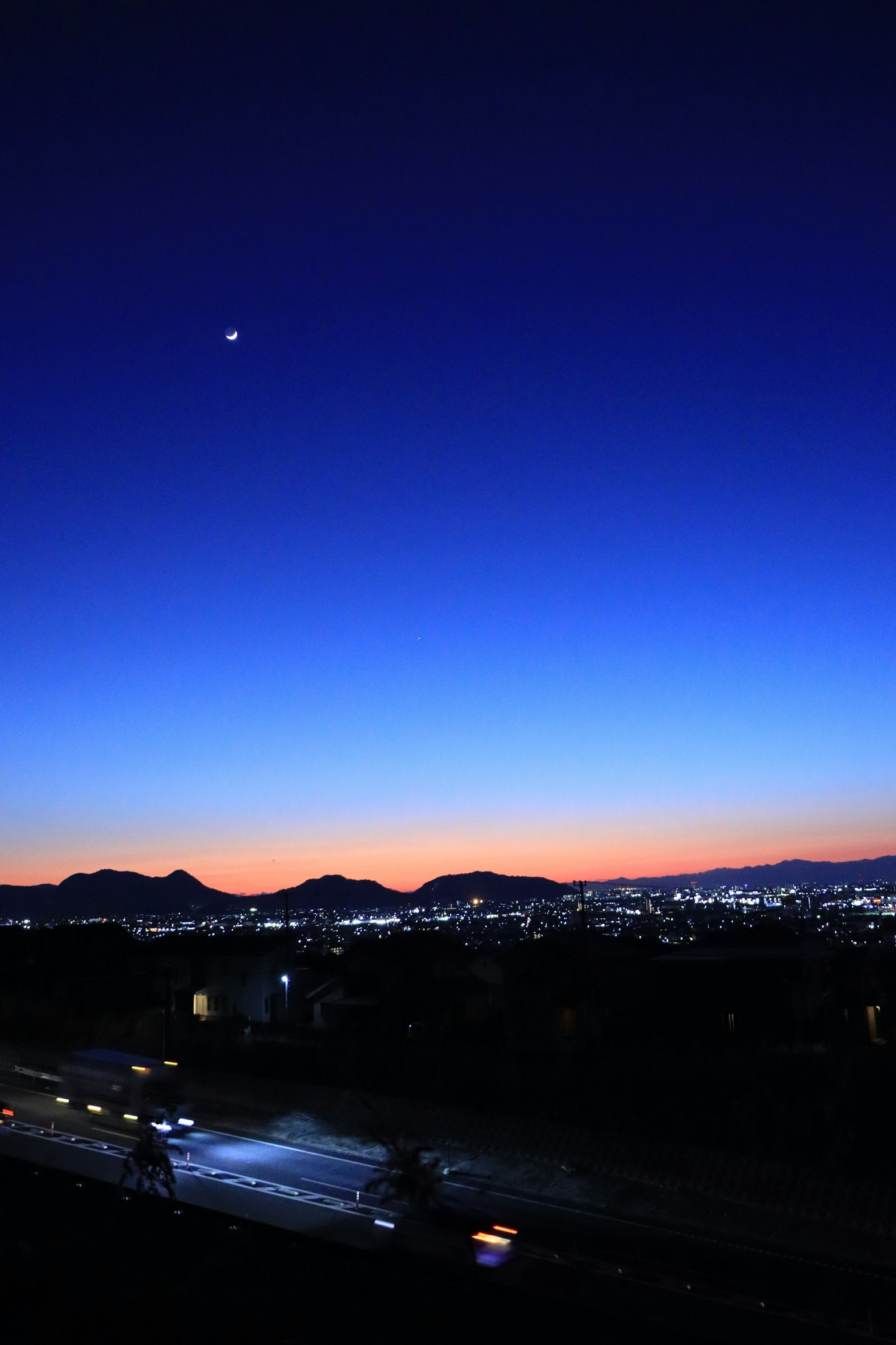 Twilight sky with silhouettes of mountains and city lights