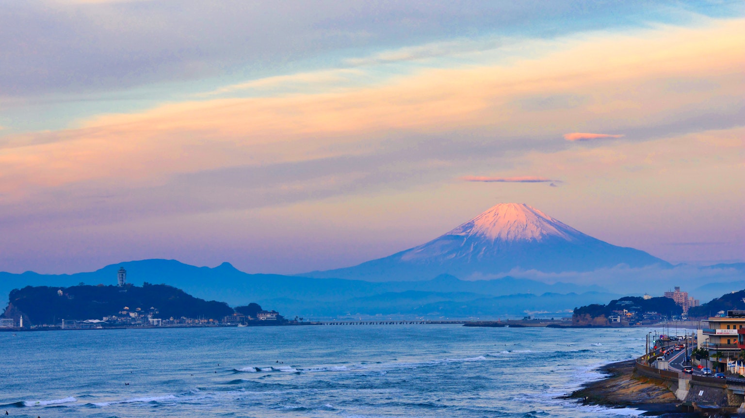 Vue panoramique du mont Fuji avec la mer au premier plan et un ciel de coucher de soleil coloré