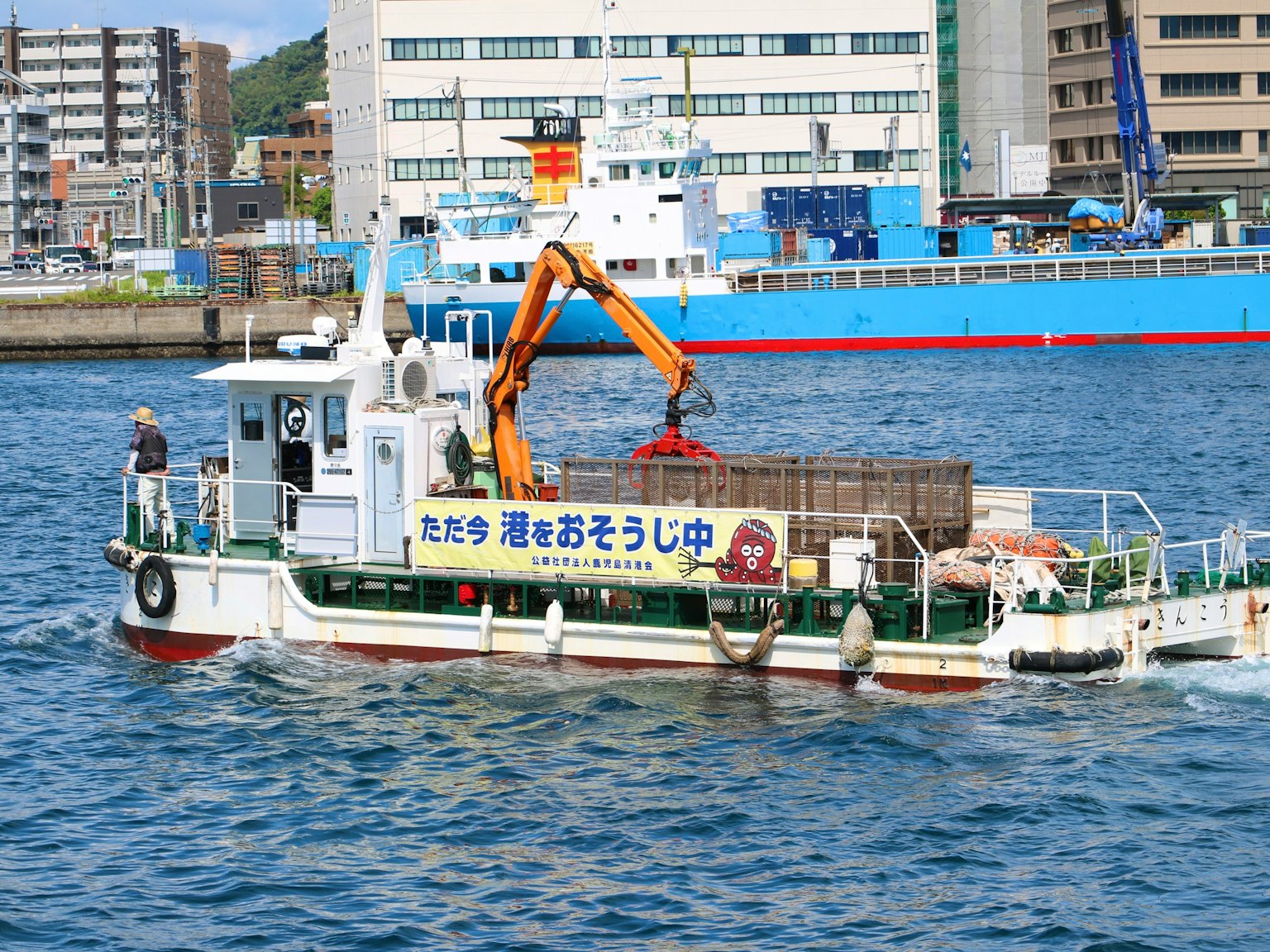 Kapal dilengkapi crane yang bekerja di pelabuhan dengan bangunan sekitar