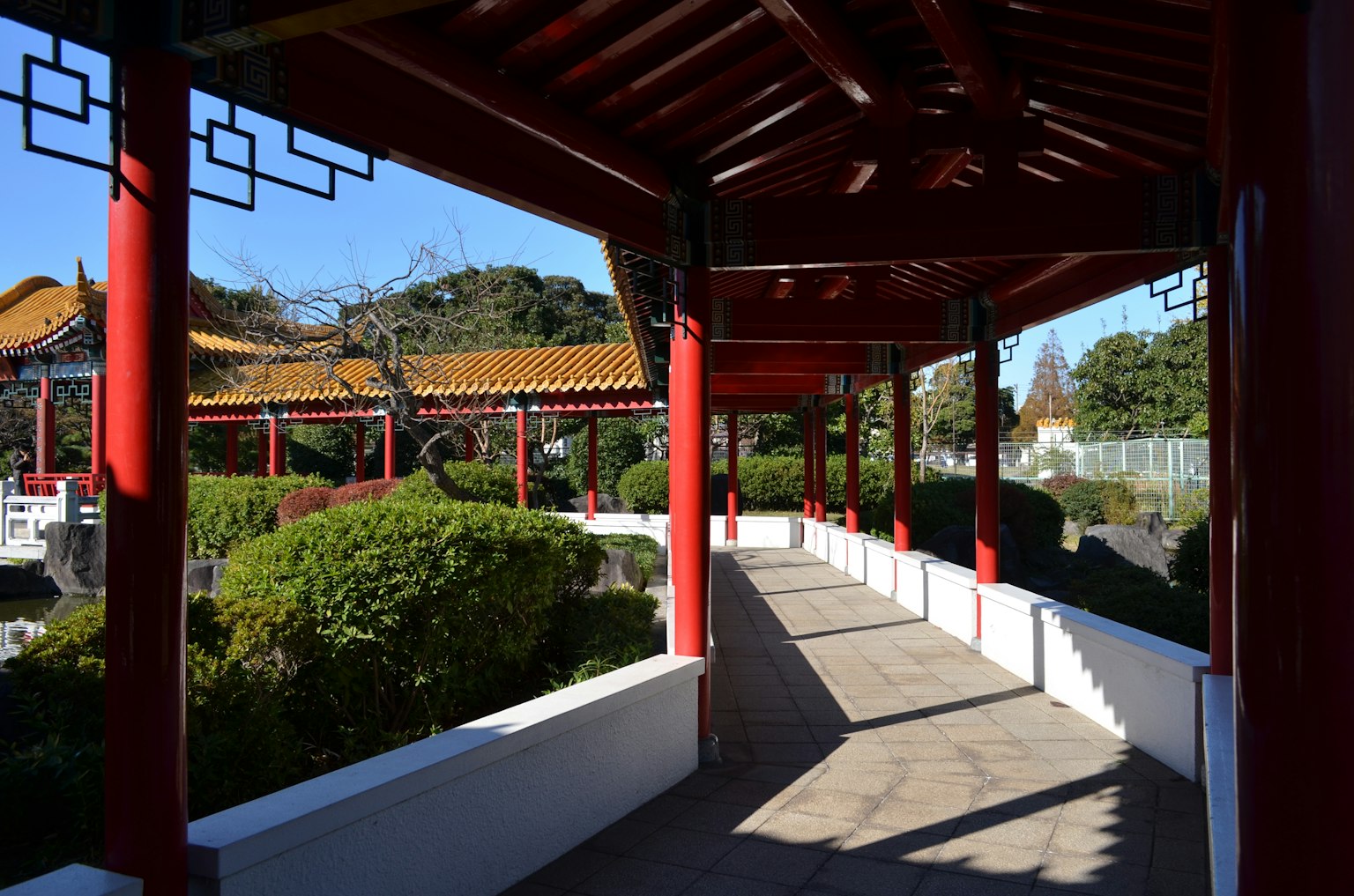 Corridoio in stile cinese con colonne e tetto rosso in un giardino