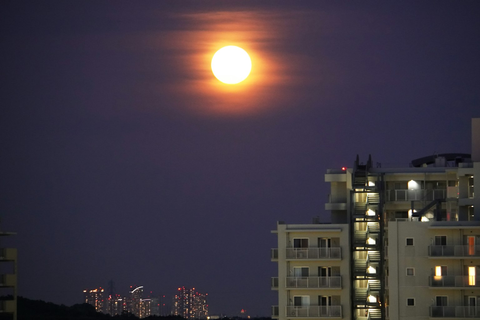 夜空中明亮的滿月與高樓大廈的輪廓
