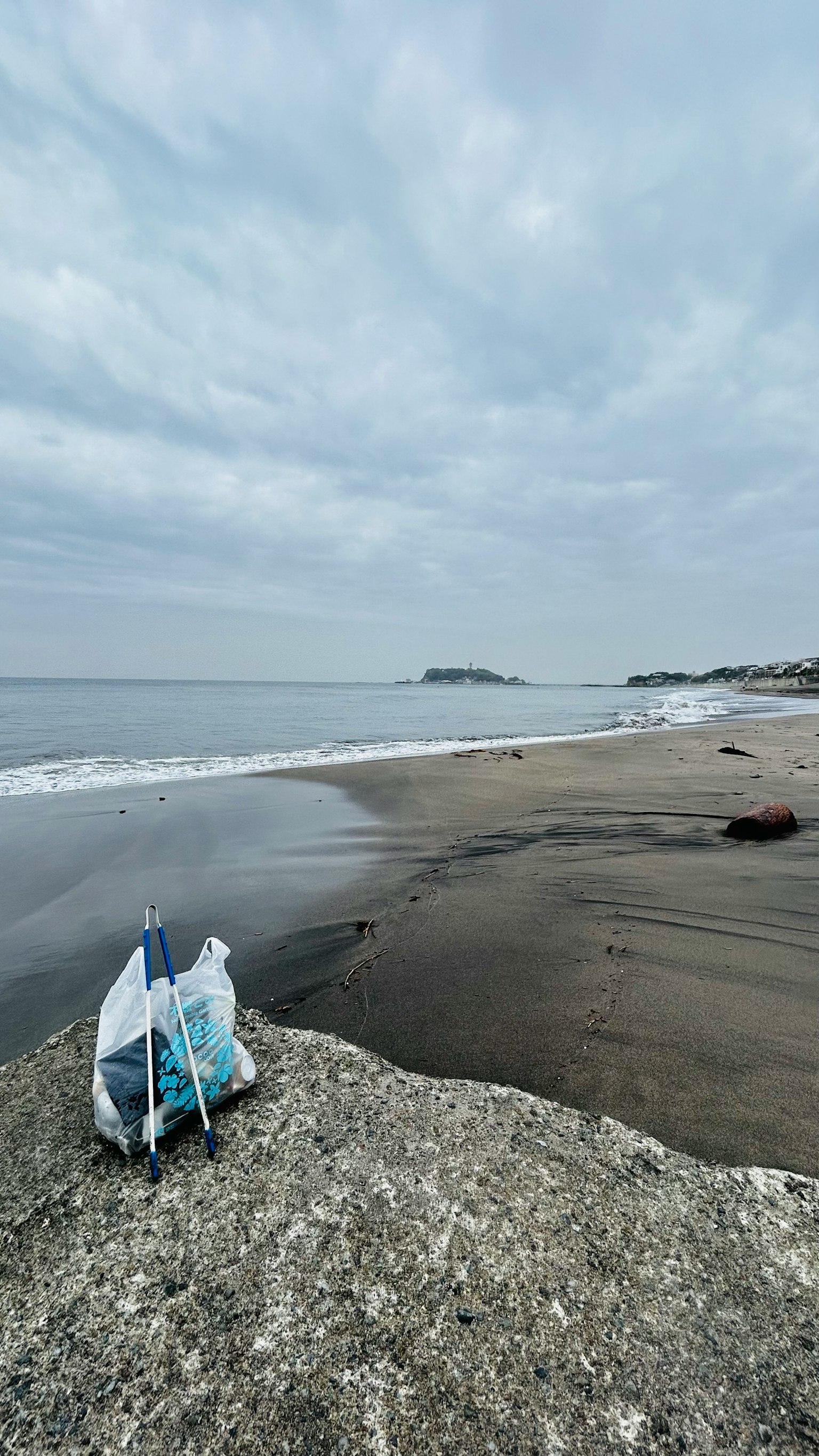 海滩岩石上的包和阴云密布的天空下的海洋景观