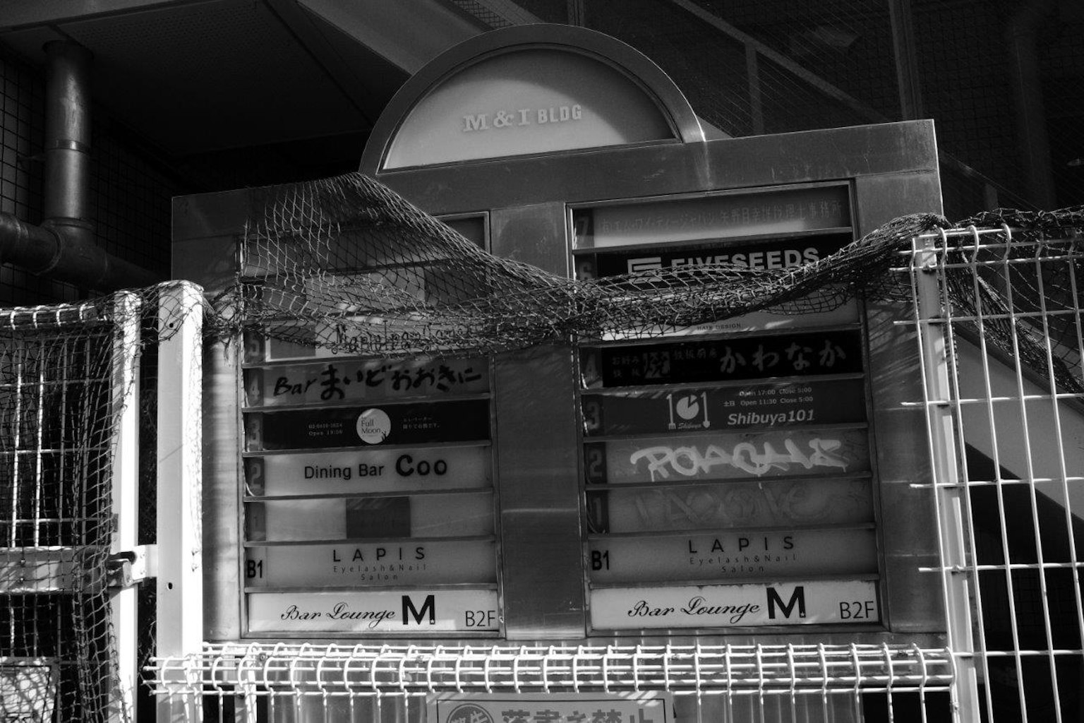 Image en noir et blanc d'un ancien tableau d'affichage avec une clôture
