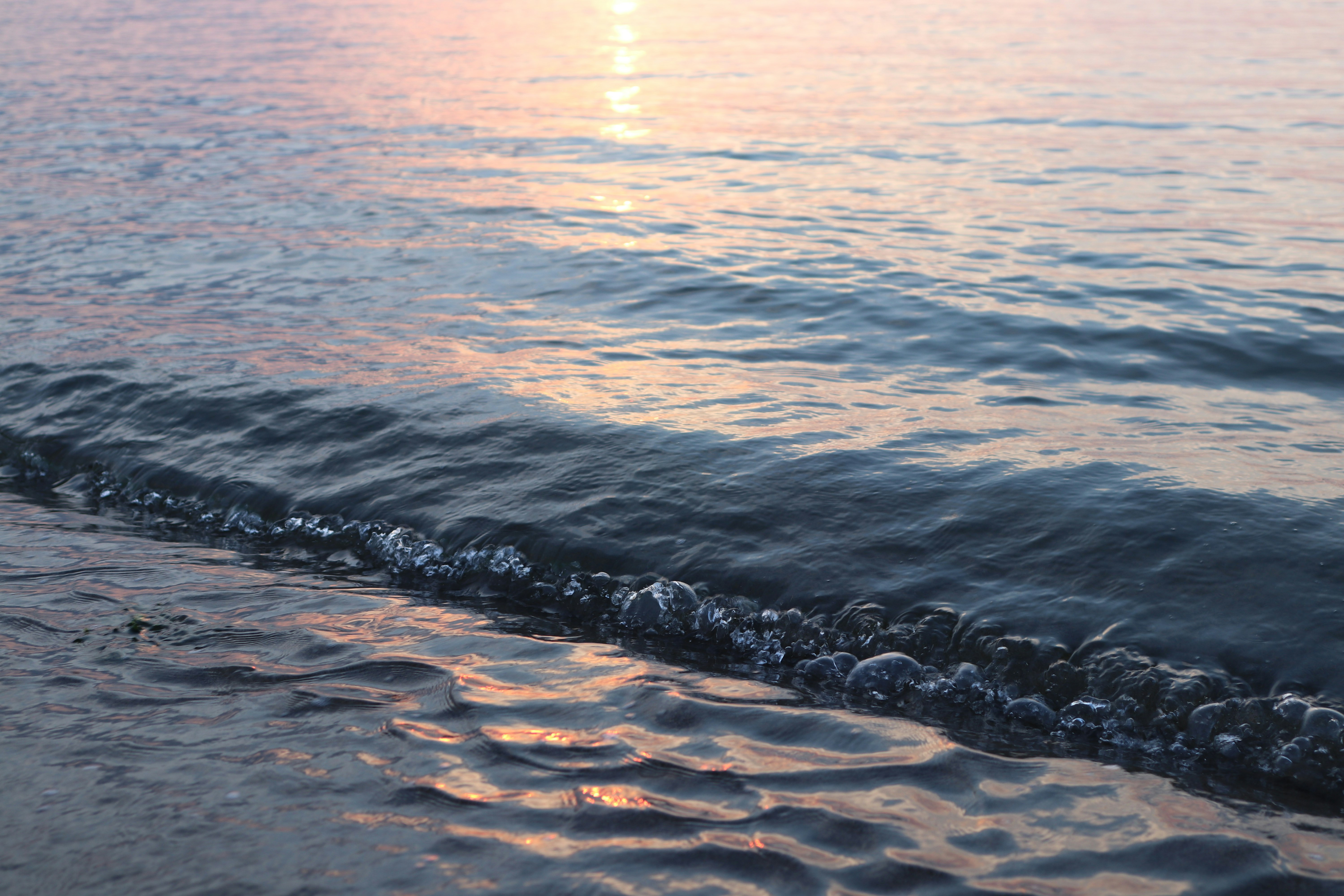 夕日に照らされた波打ち際の海面