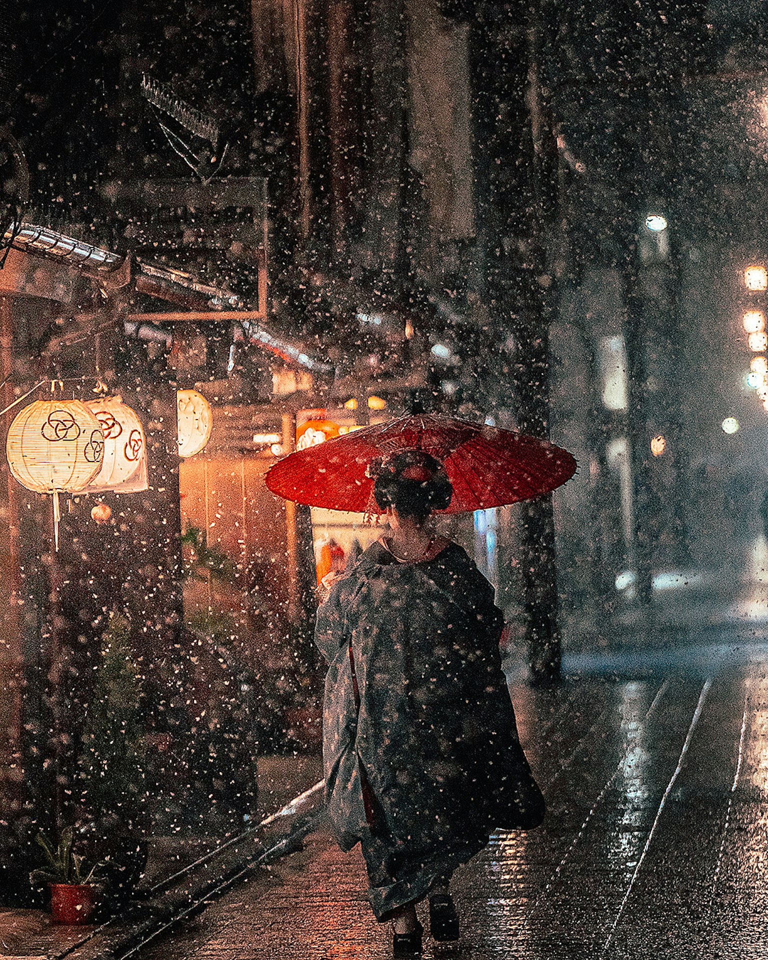 一位女性在城市中雨中撐著紅色雨傘行走