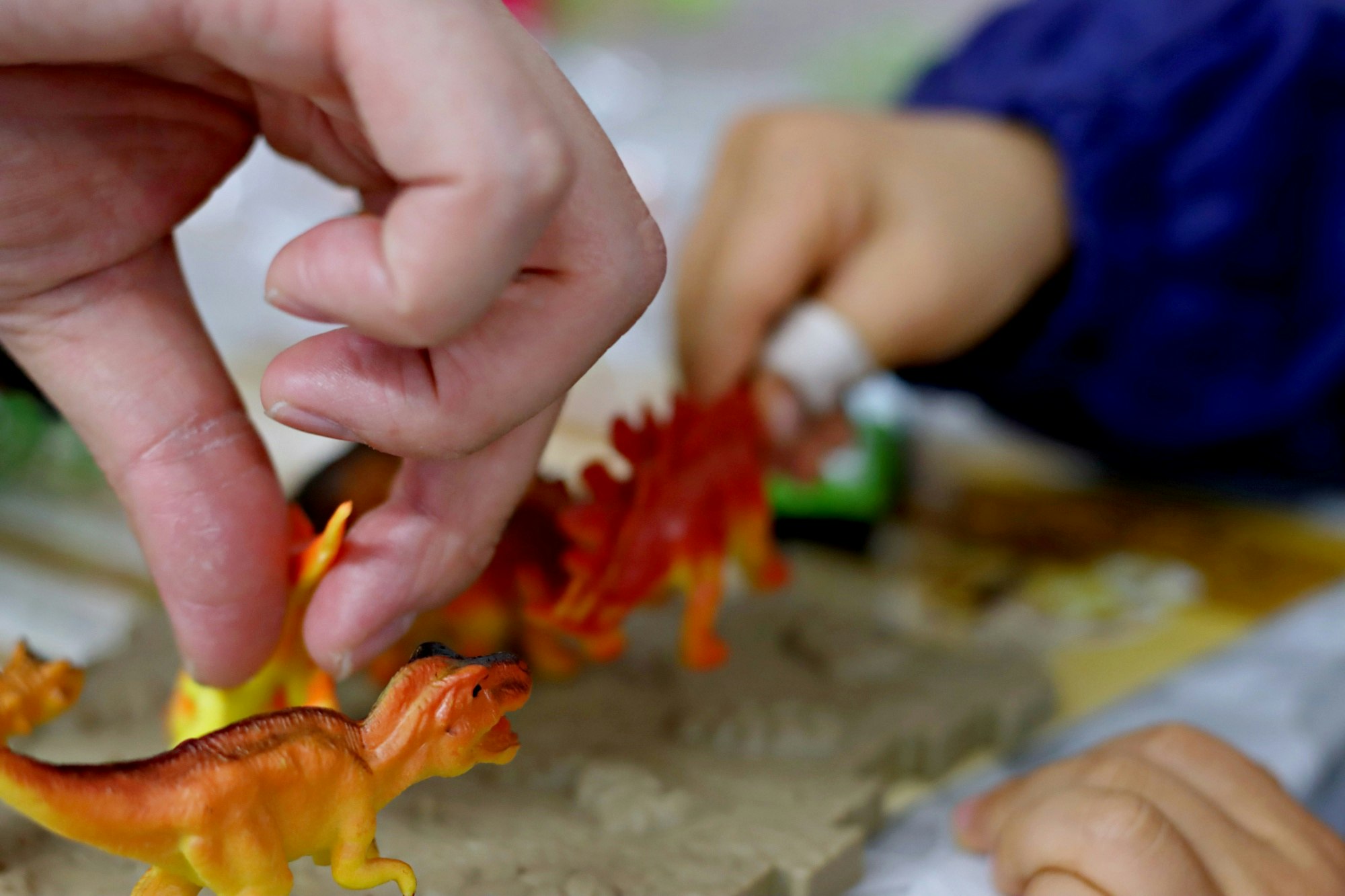 child’s hands playing with dinosaur toys