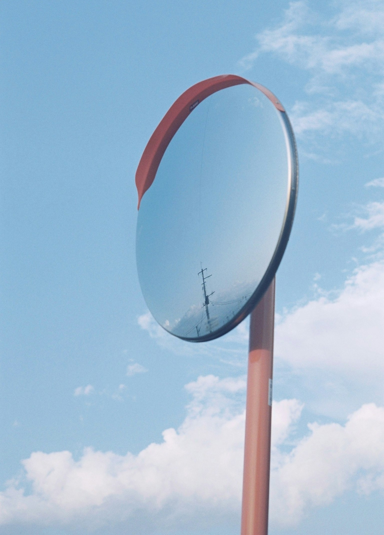 Large mirror traffic sign under blue sky