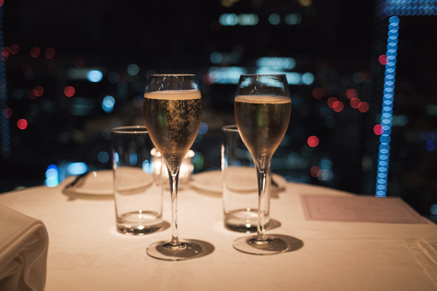 Bicchieri di champagne e bicchieri d'acqua su un tavolo con vista notturna della città