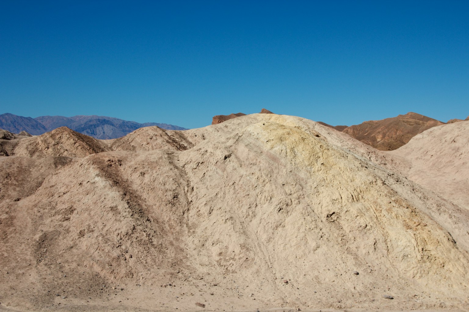A landscape of sand dunes under a blue sky