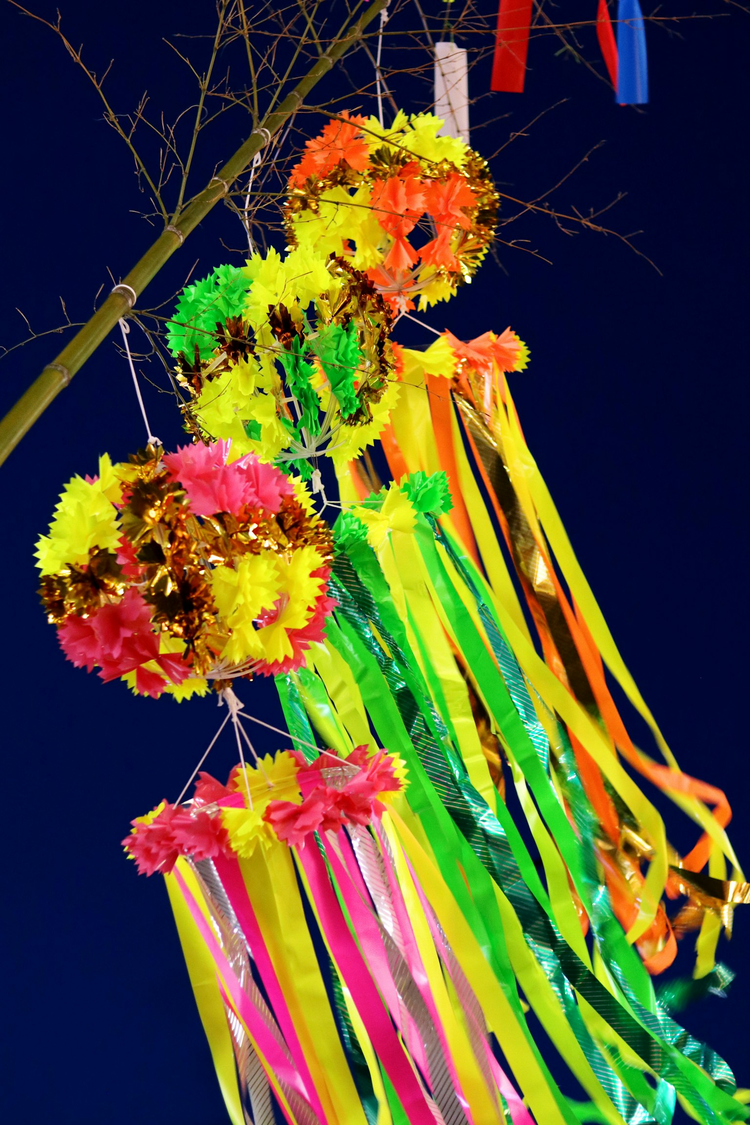 Colorful decorations with flowers and ribbons hanging from a tree